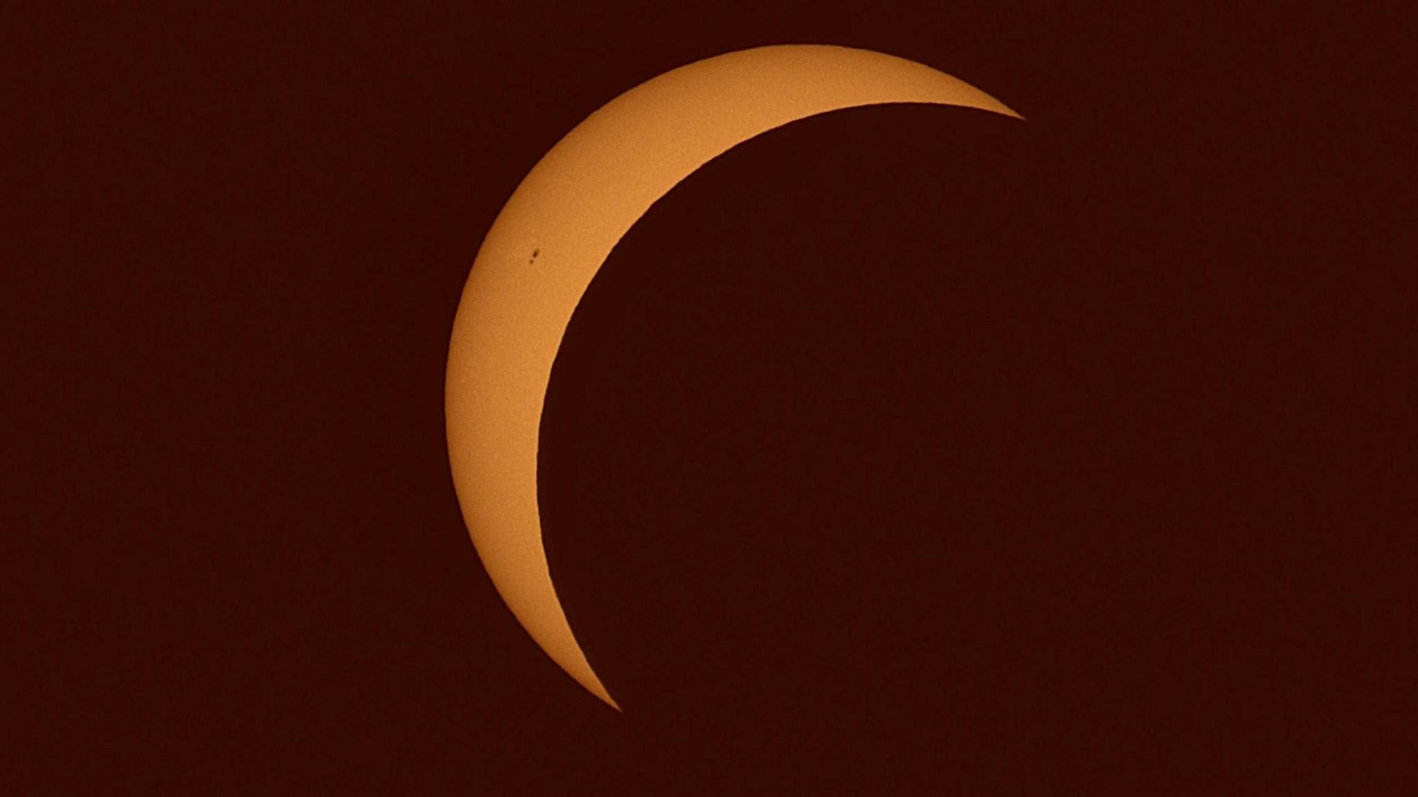 An orange crescent Sun as seen in the skies above St Mellion.