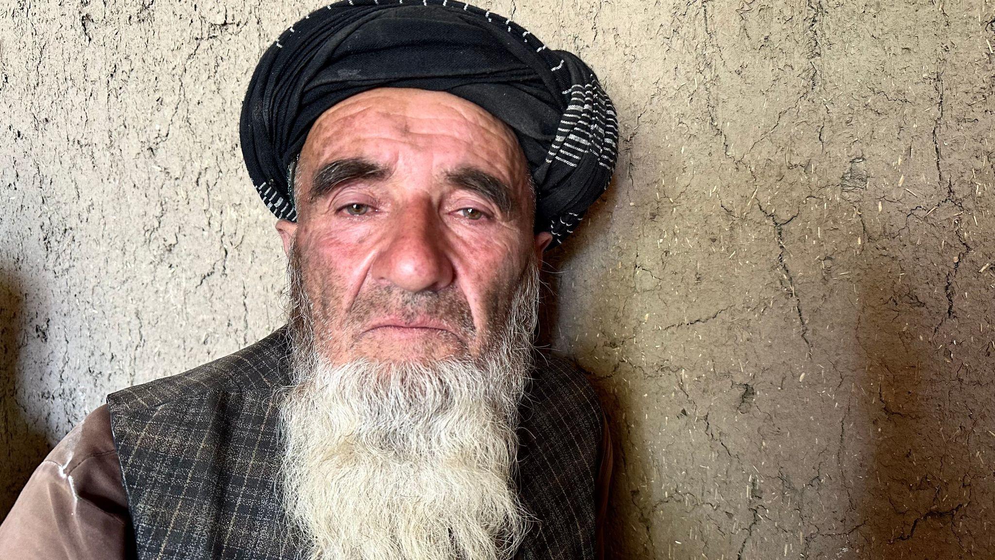 Ahmad Khan looks at the camera with a grieving expression, as he's pictured in a head-and-shoulders portrait against a light coloured wall.