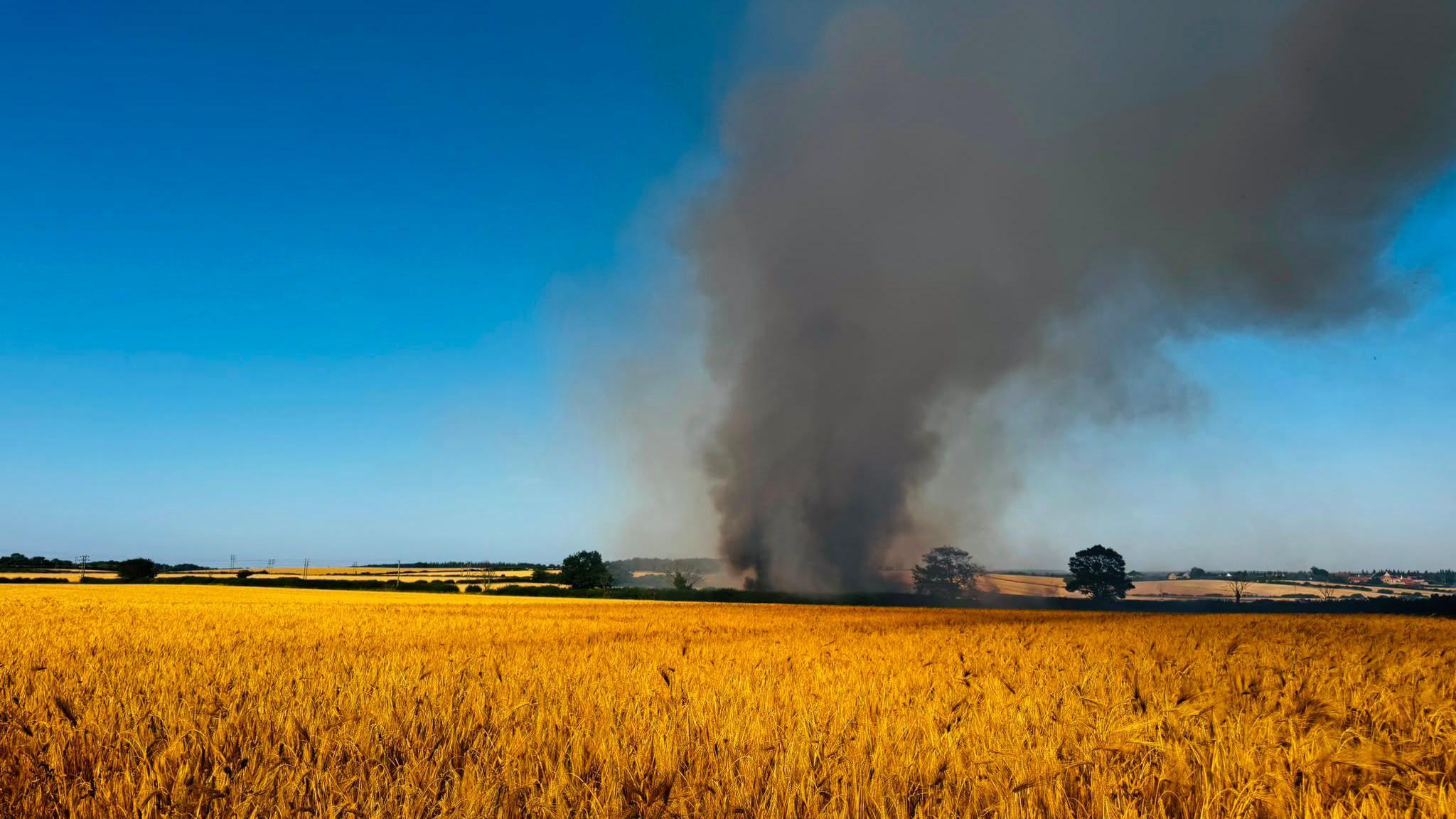 Wildfire in a farm field in Palterton, near Chesterfield, Derbyshire with smoke billowing from a field of dry crops