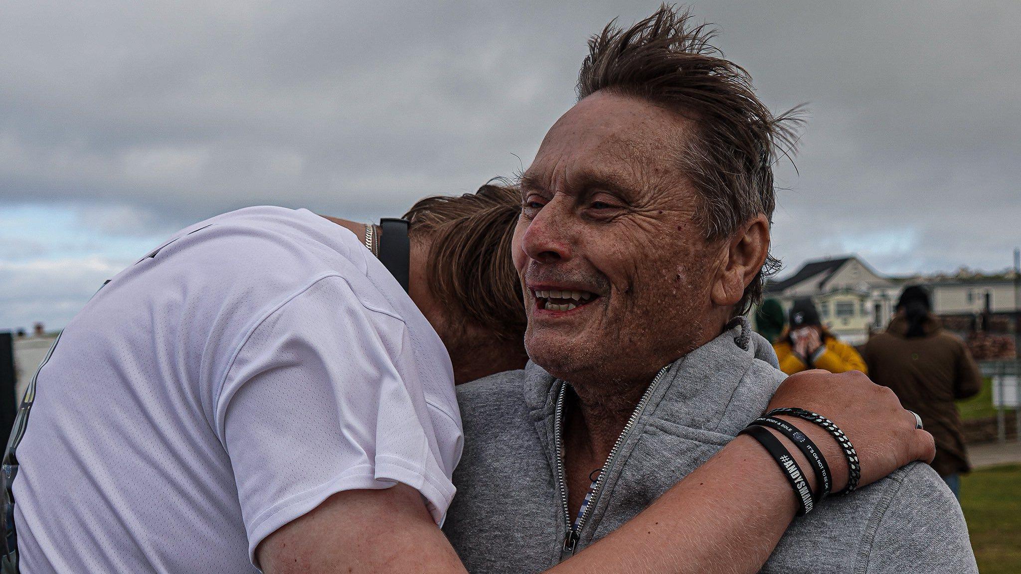 Marcus and his dad shown hugging.