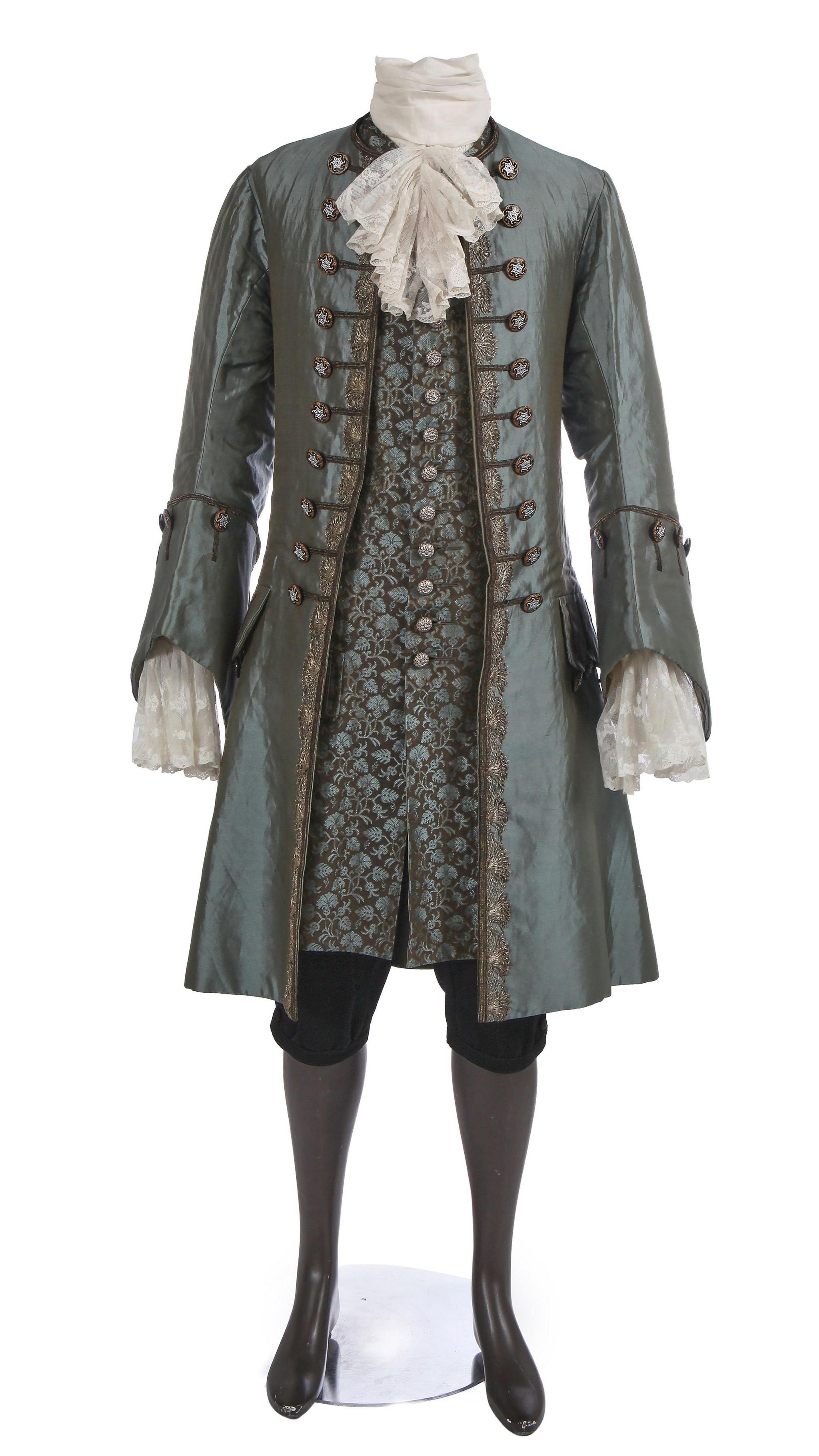 A 1750s style teal-bue silk frock coat edged in silver lace featuring deep cuffs and front closure with black cut-glass buttons painted silver and gold, matching brocaded silk waistcoat woven with teal blue floral repeats on a brown silk ground, lined in pale green-bue silk, domed silvered metal filigree buttons, a pair of black wool breeches and a white cotton 18th century style shirt with deep lace cuffs.