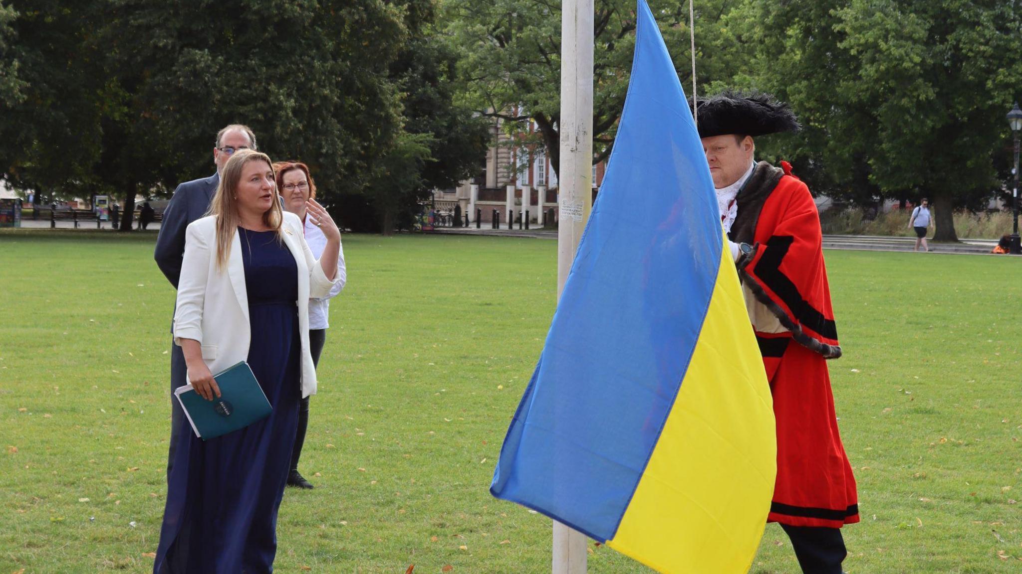 Antonina Grebeniuk speaking while the lord mayor raises a Ukrainian flag on College Green