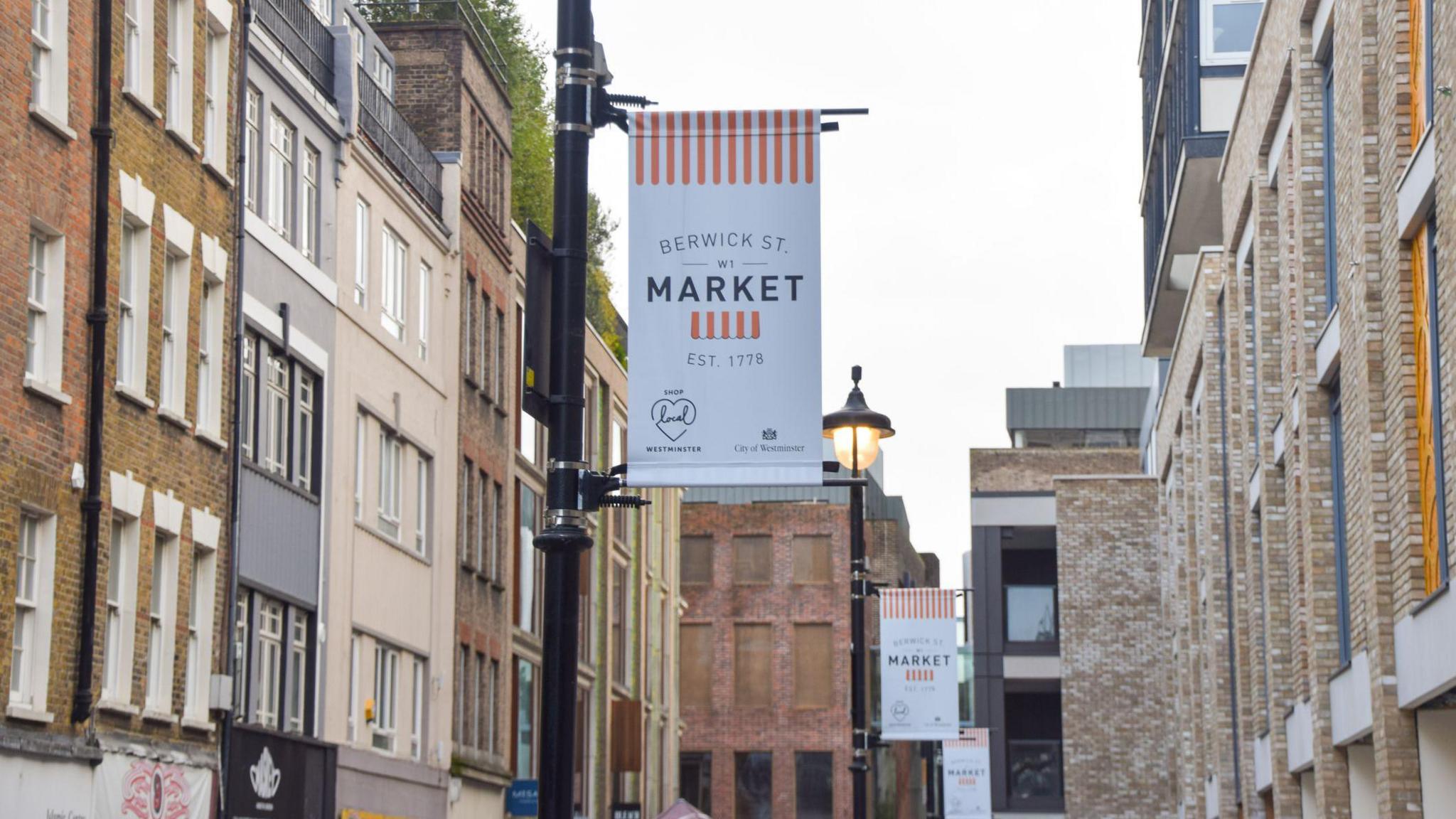 General view of Berwick Street Market signs hanging on lamp posts.