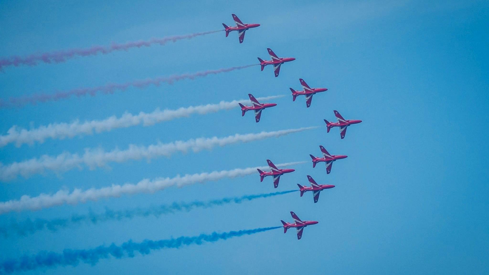 Nine Red Arrows with red and white smoke trails against a blue sky, over Aberdeen.