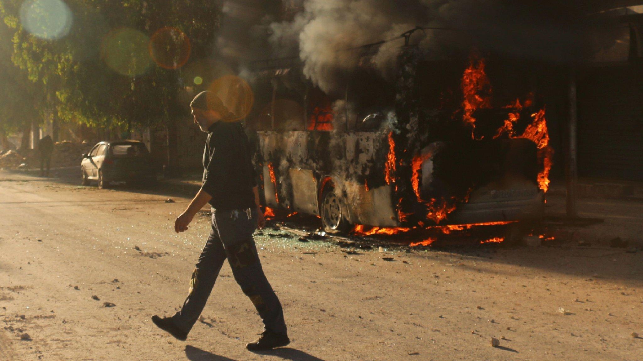 Man walks past a bust set ablaze following a reported air strike in rebel-held Salahuddin district of Aleppo (25 September 2016)