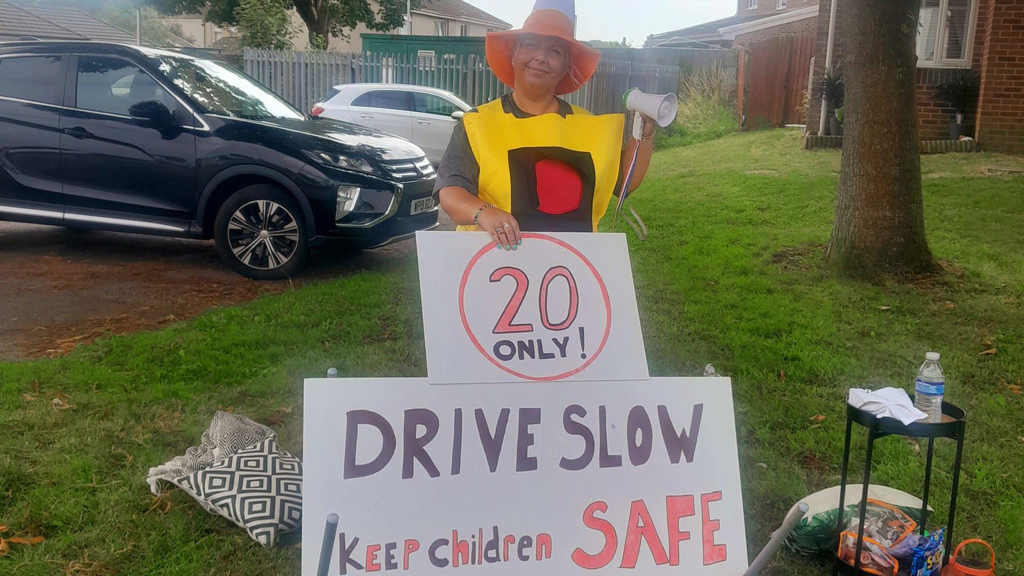 Faye smiles for a picture dressed as a traffic cone with her speed warning sign