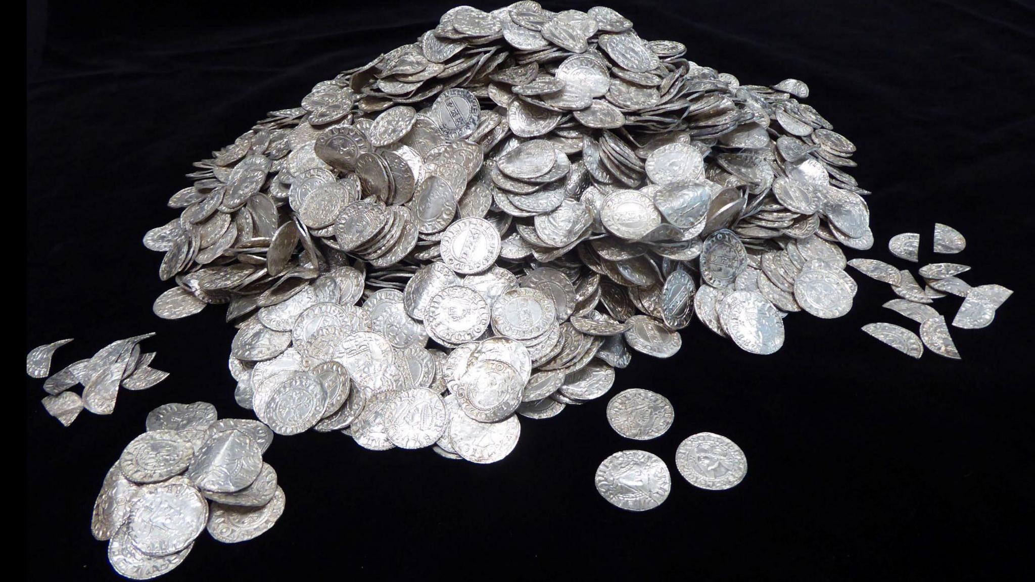A pile of silver coins on a black background. Mostly whole but some are split apart.
