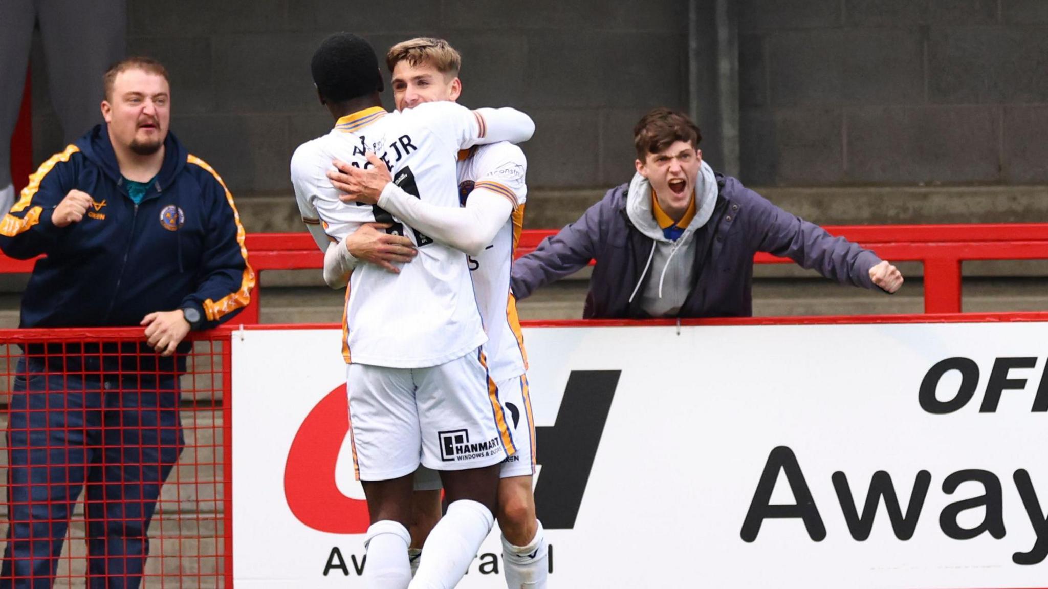 George Lloyd is joined by Shrewsbury team-mate Charles Sagoe Jnr and two away fans to help celebrate one of his two late strikes in the 5-3 win at Crawley in October