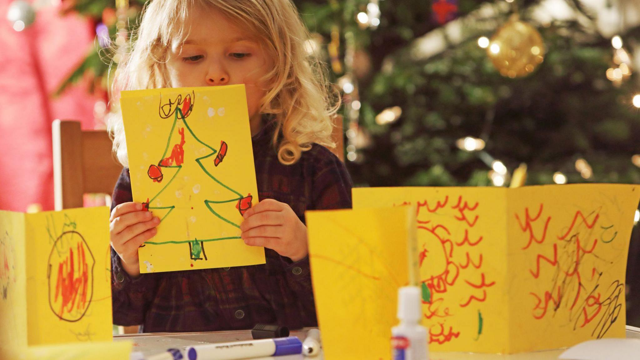 Young child holding up homemade Christmas card. 