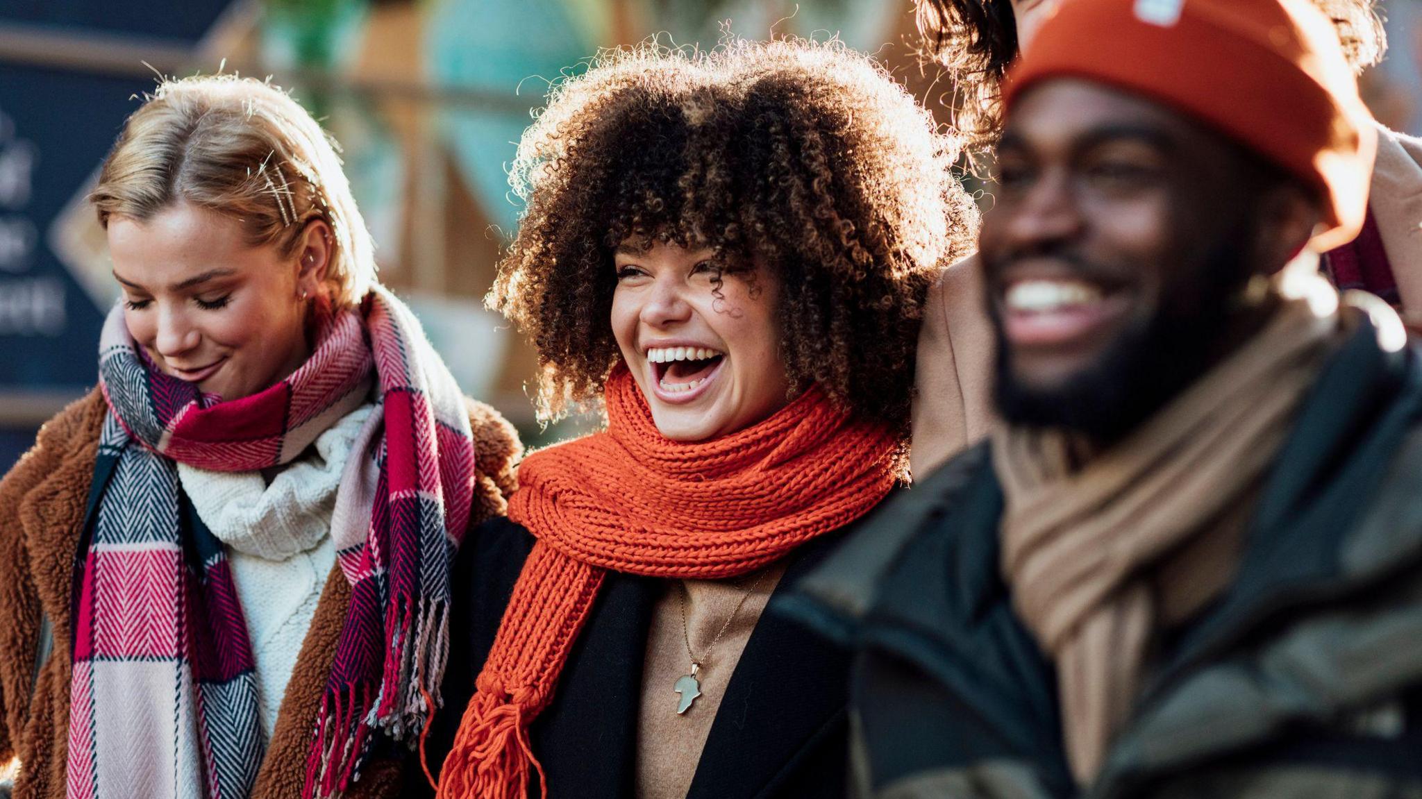 Three people wearing winter coats and scarves