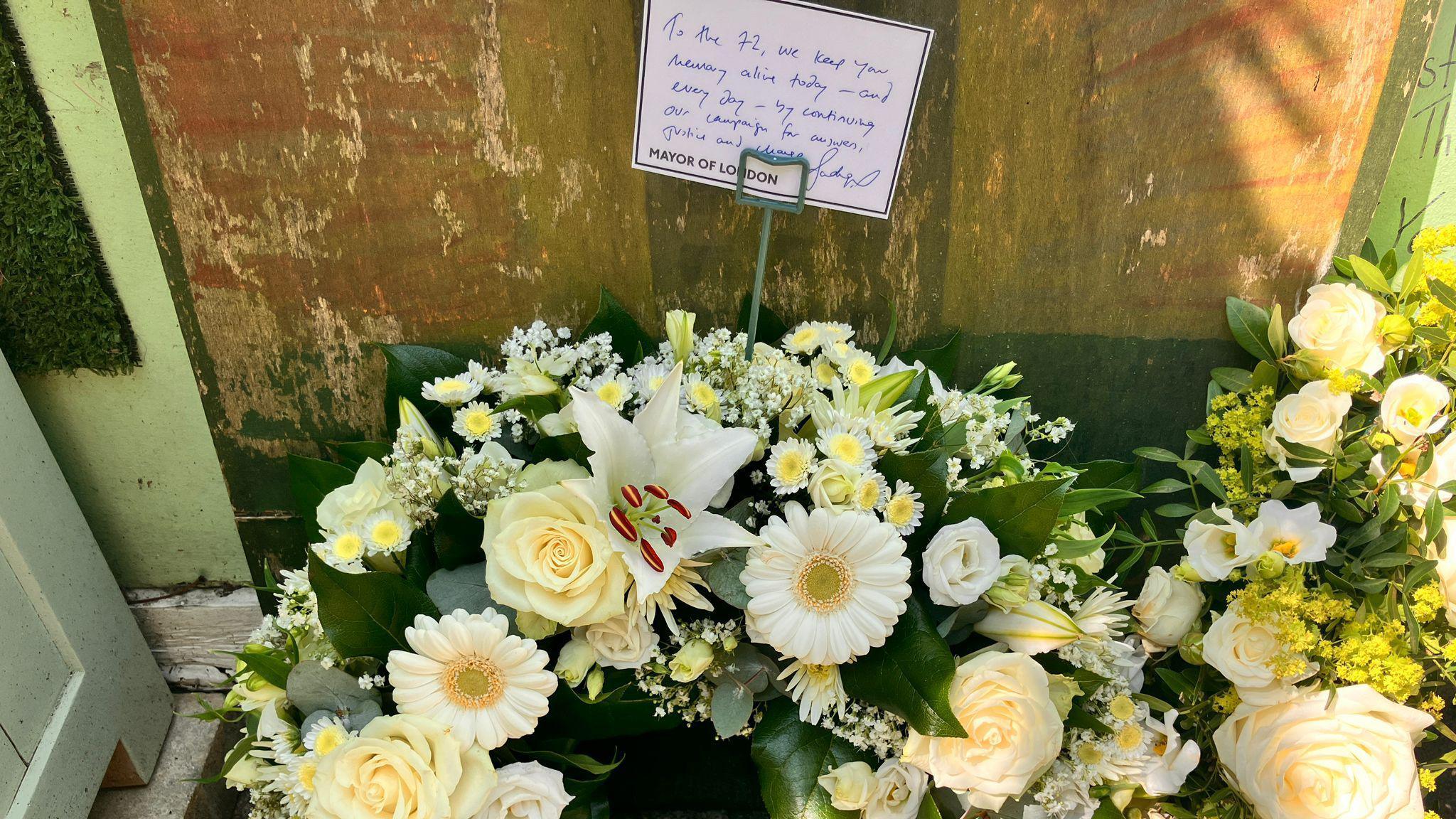 A floral wreath made up of light yellow and white flowers with a message attached saying: "To the 72. We keep your memory alive today and every day by continuing our campaign for answers, justice and change. Mayor of London"