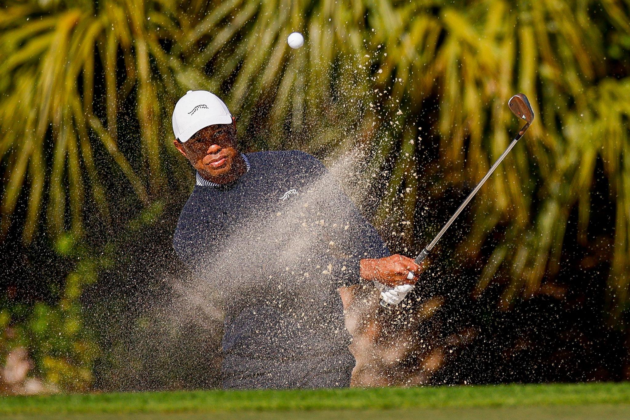 Tiger Woods hits out of a greenside bunker on the fourth hole during the first round of the PNC Championship at Ritz-Carlton Golf Club in Orlando, Florida