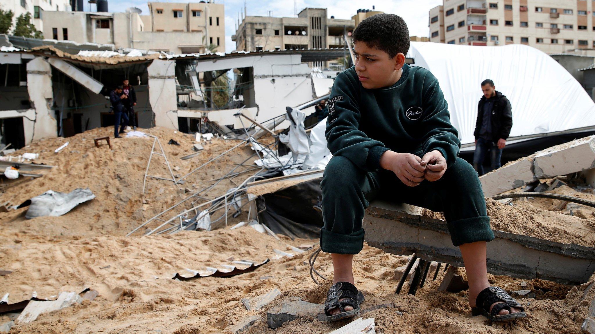 A Palestinian boy sits near a Hamas site in Gaza City destroyed in an Israeli air strike (15 March 2019)