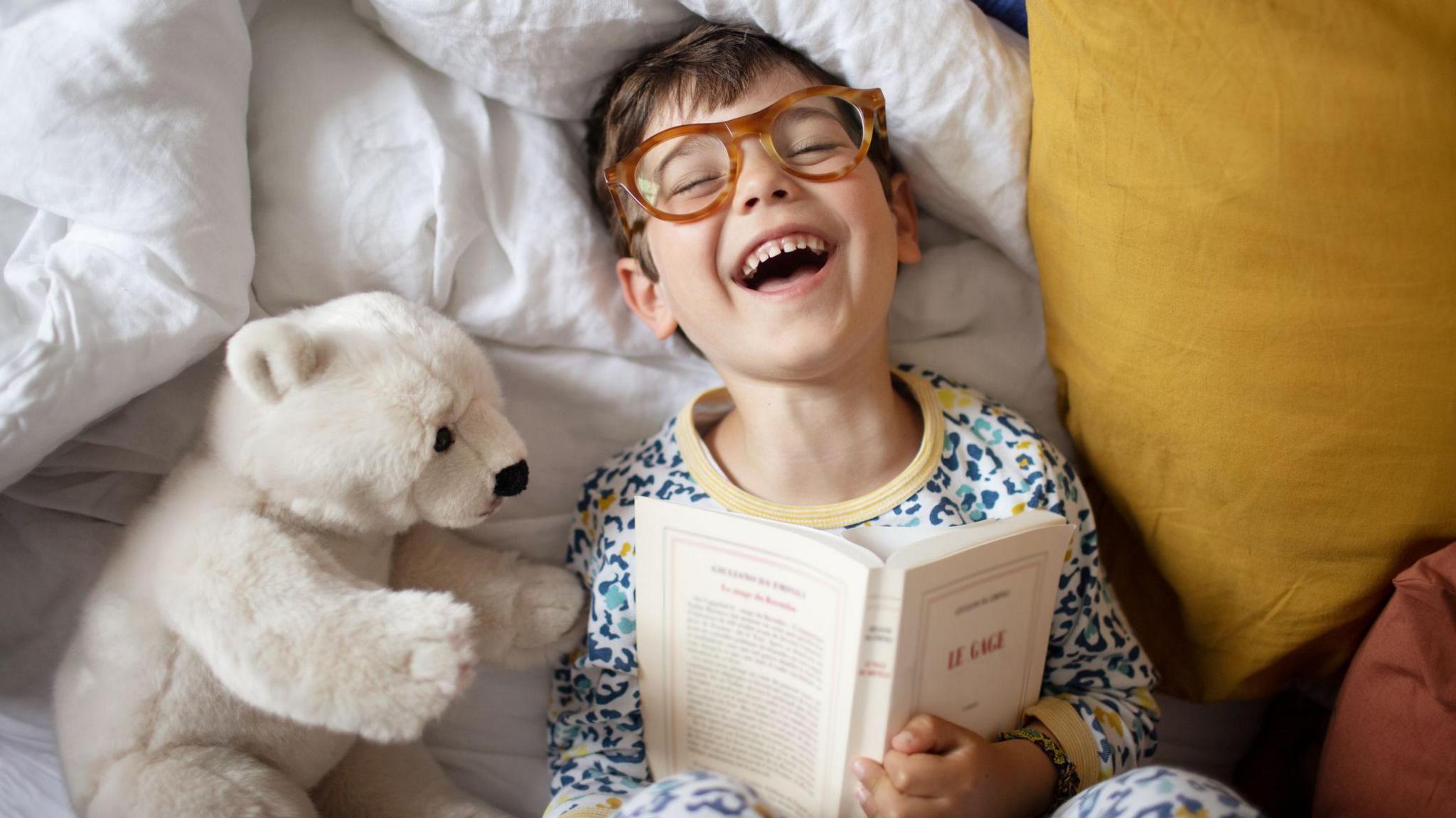 a boy laughing whilst reading a book