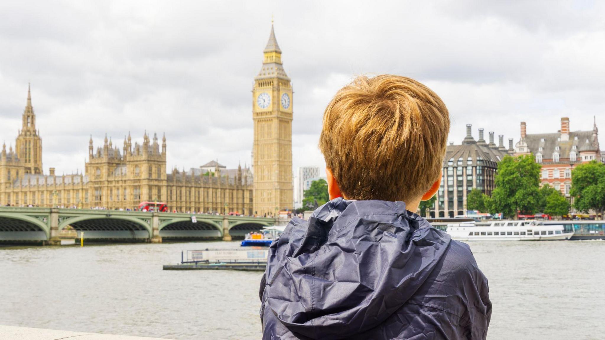 A child looking over the Thames towards the UK Houses of Parliament. 