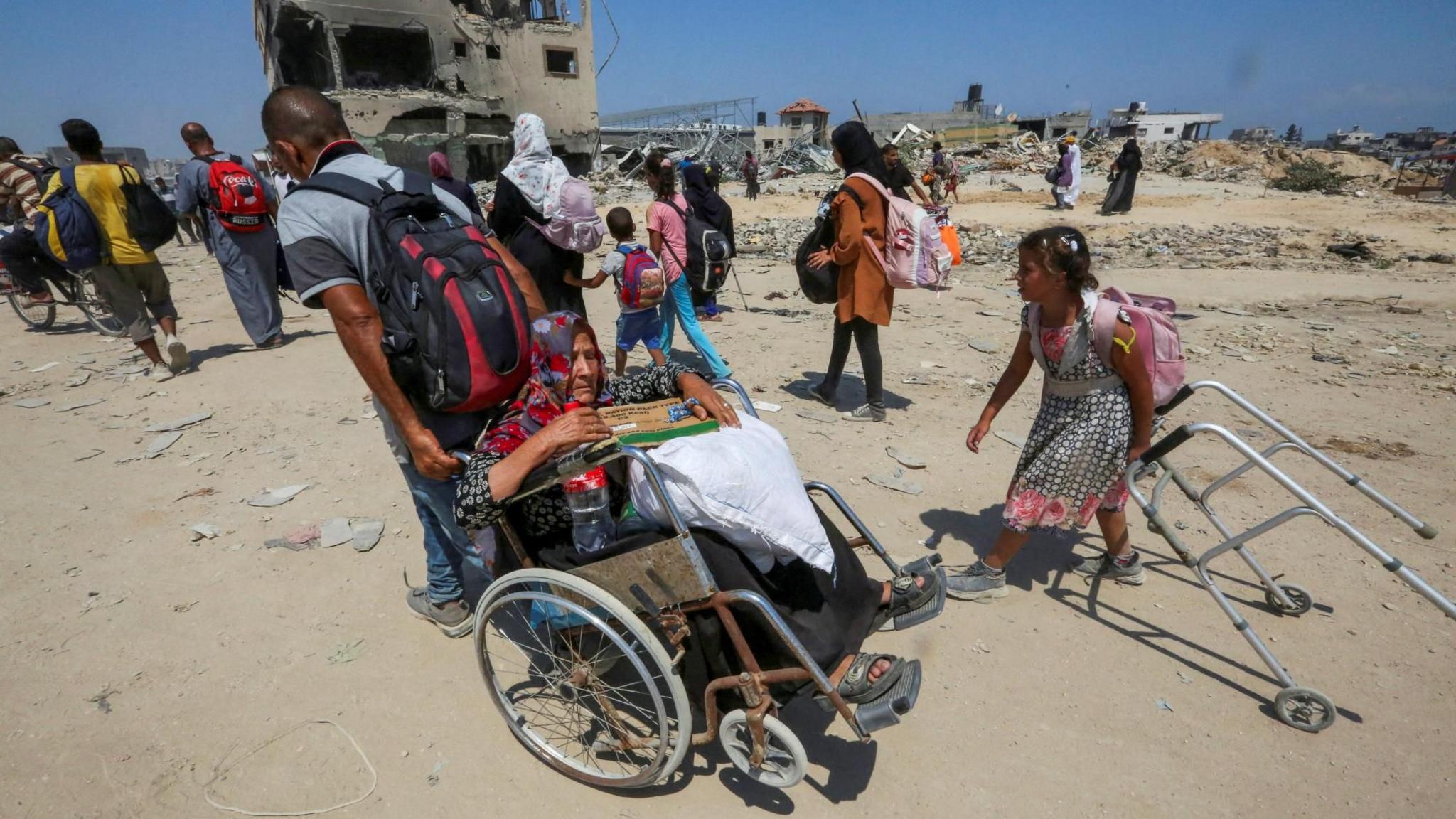 A Palestinian woman sitting on a wheelchair is pulled by a man as they flee eastern Khan Younis in response to an Israeli evacuation order, in the southern Gaza Strip (22 July 2024)