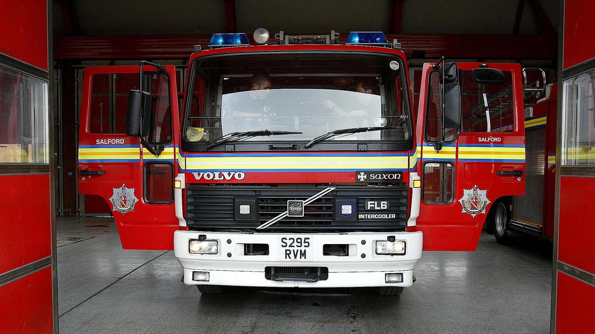 A Greater Manchester Fire and Rescue Service fire engine with both doors open.