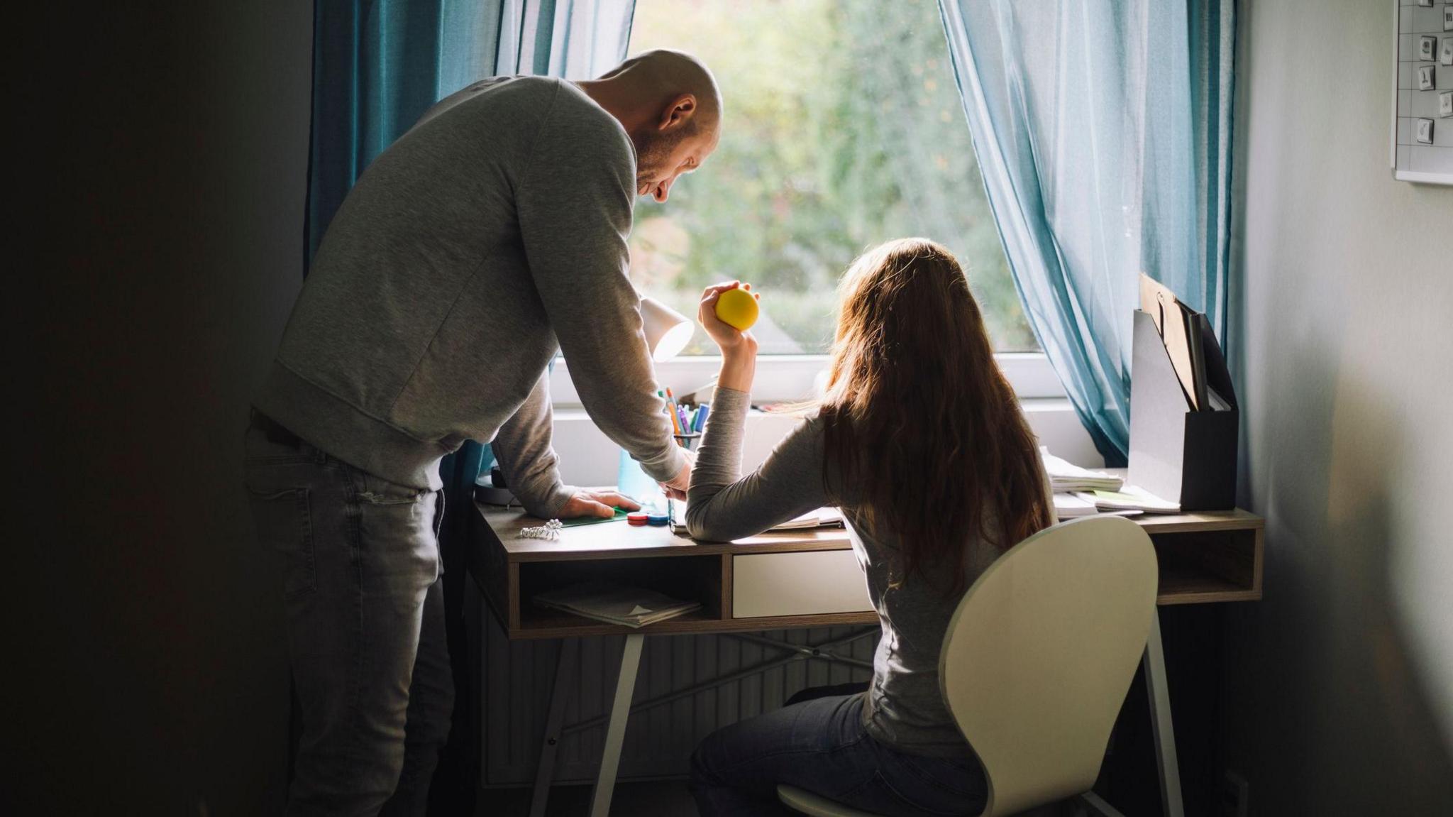 Father helping daughter study at home (stock image)