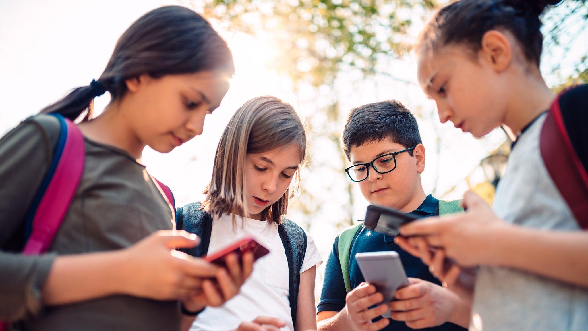 Four children looking at their phones