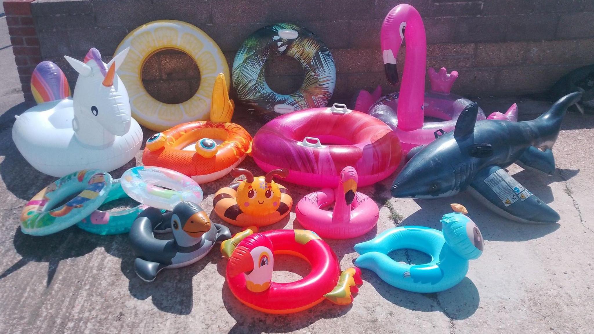 Large pile of inflatable toys collected from Weymouth beach including from left to right a unicorn, goldfish, flamingo and shark.