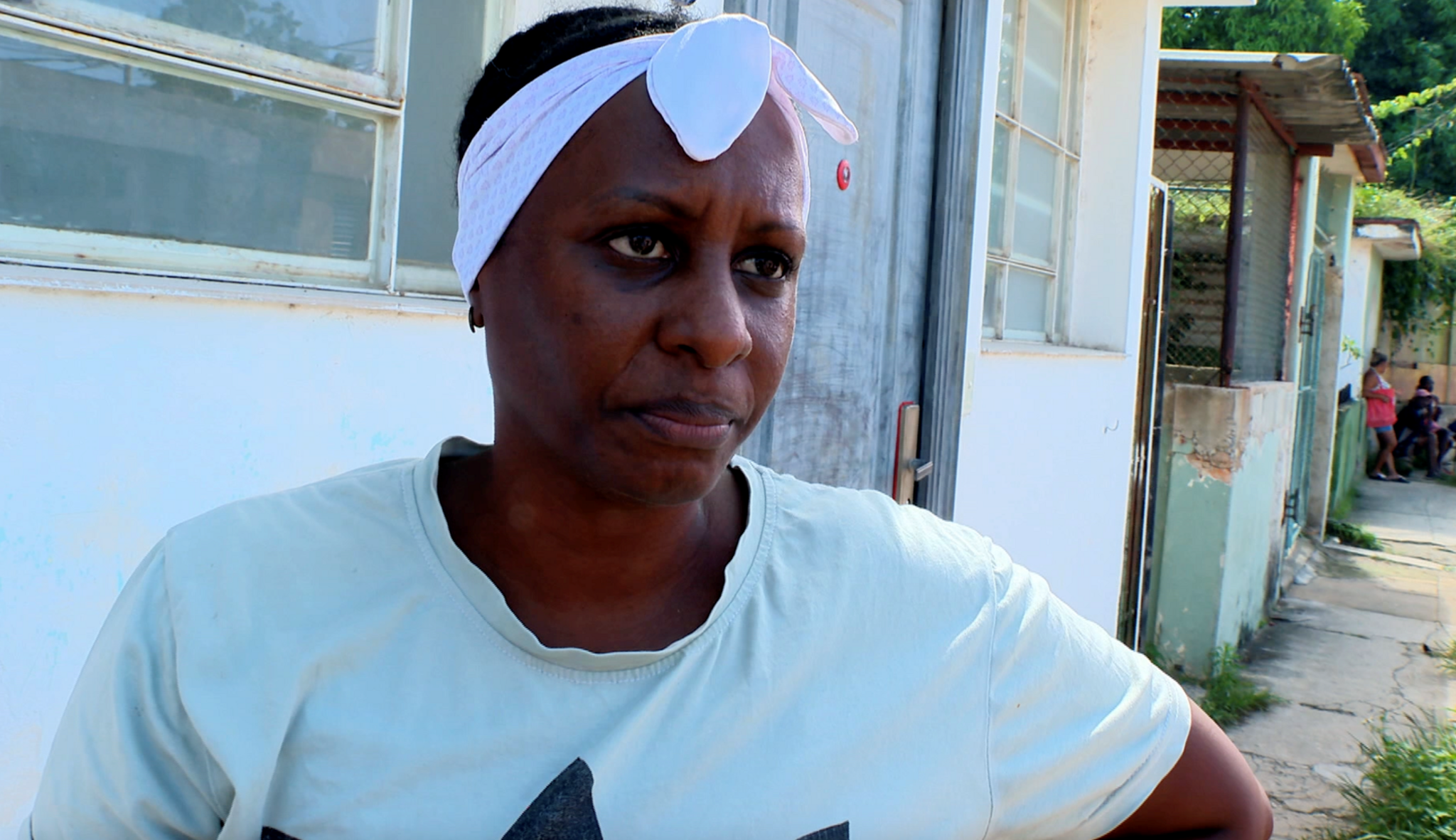 Yusely, a woman wearing a T-shirt and white headband, looks into the camera