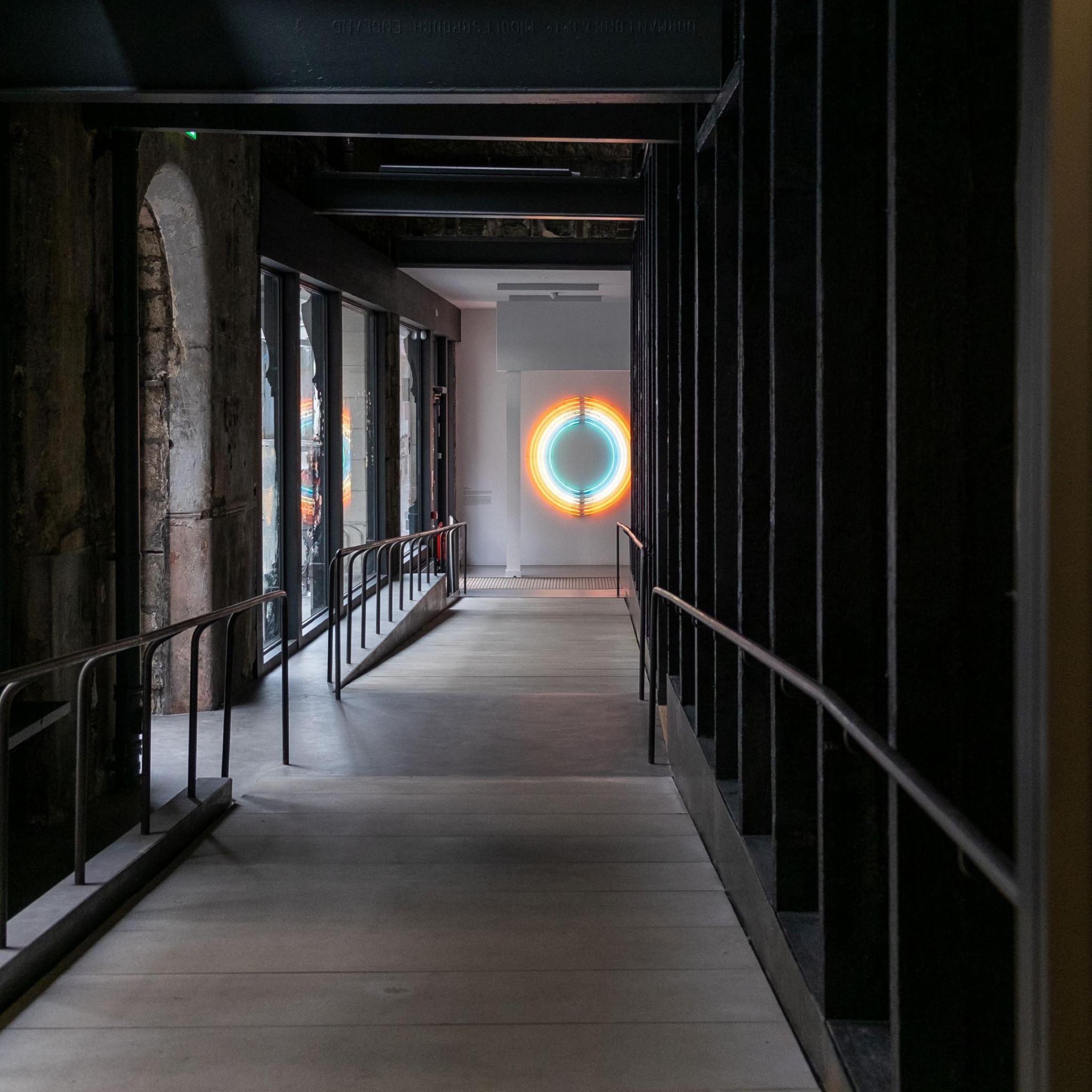 A dark corridor with a ring of rainbow light at the end