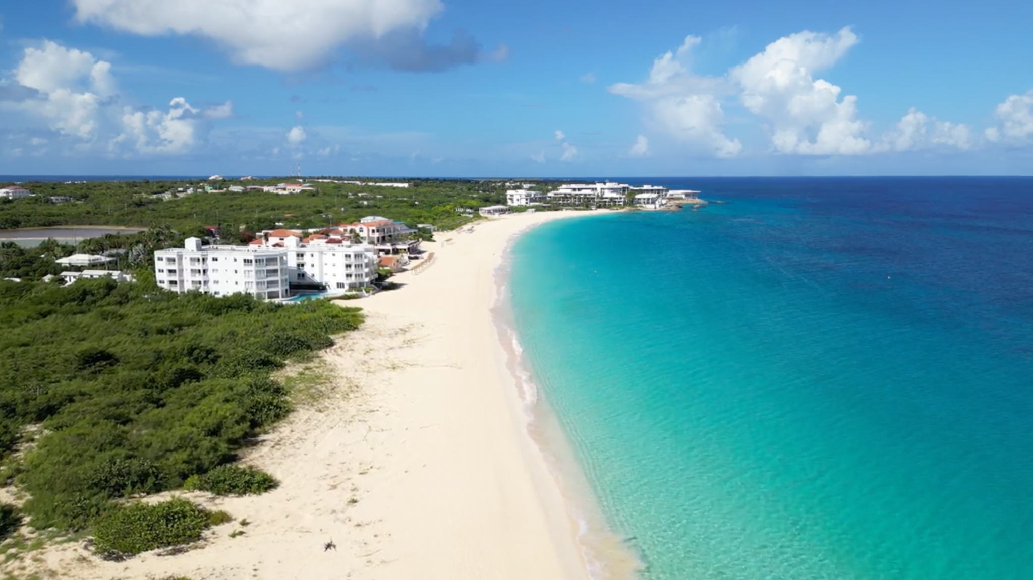 Drone shot of Anguilla, showing a bright blue sea to the right and golden sand to the left