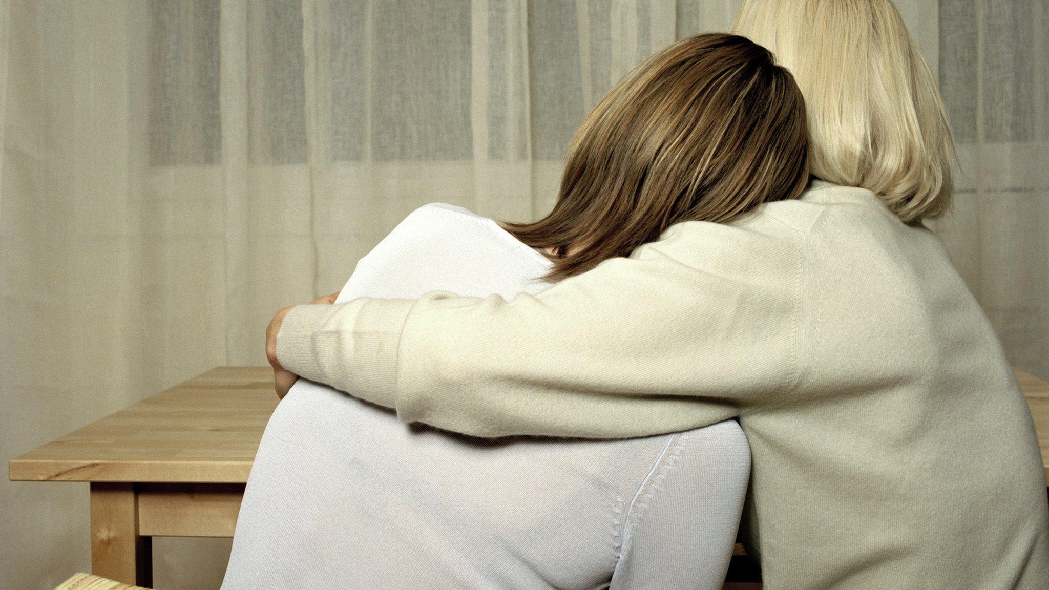 An older woman hugs a younger woman