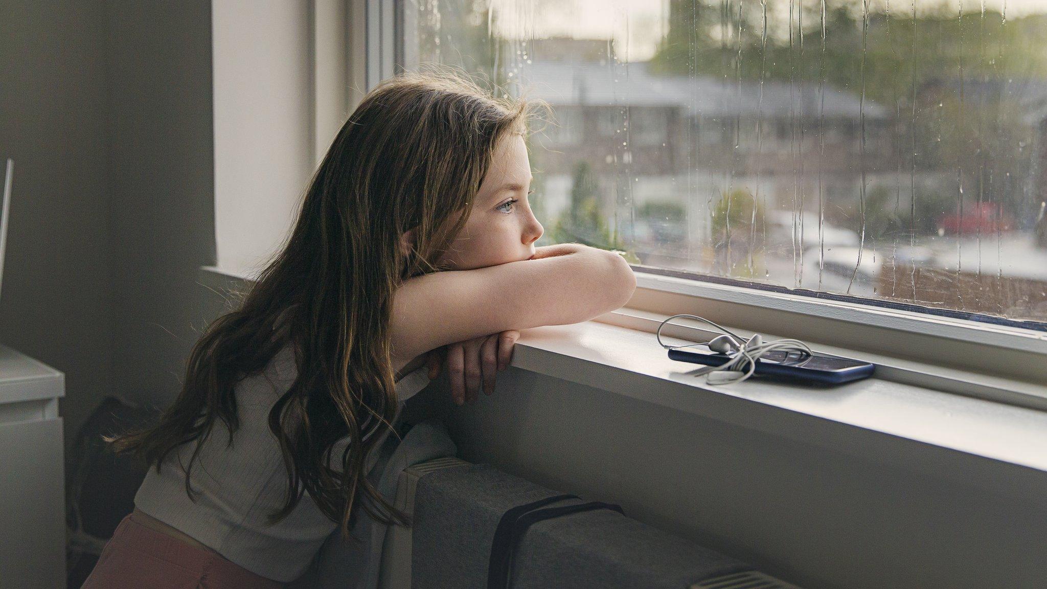 Stock image of a young girl looking out of a window