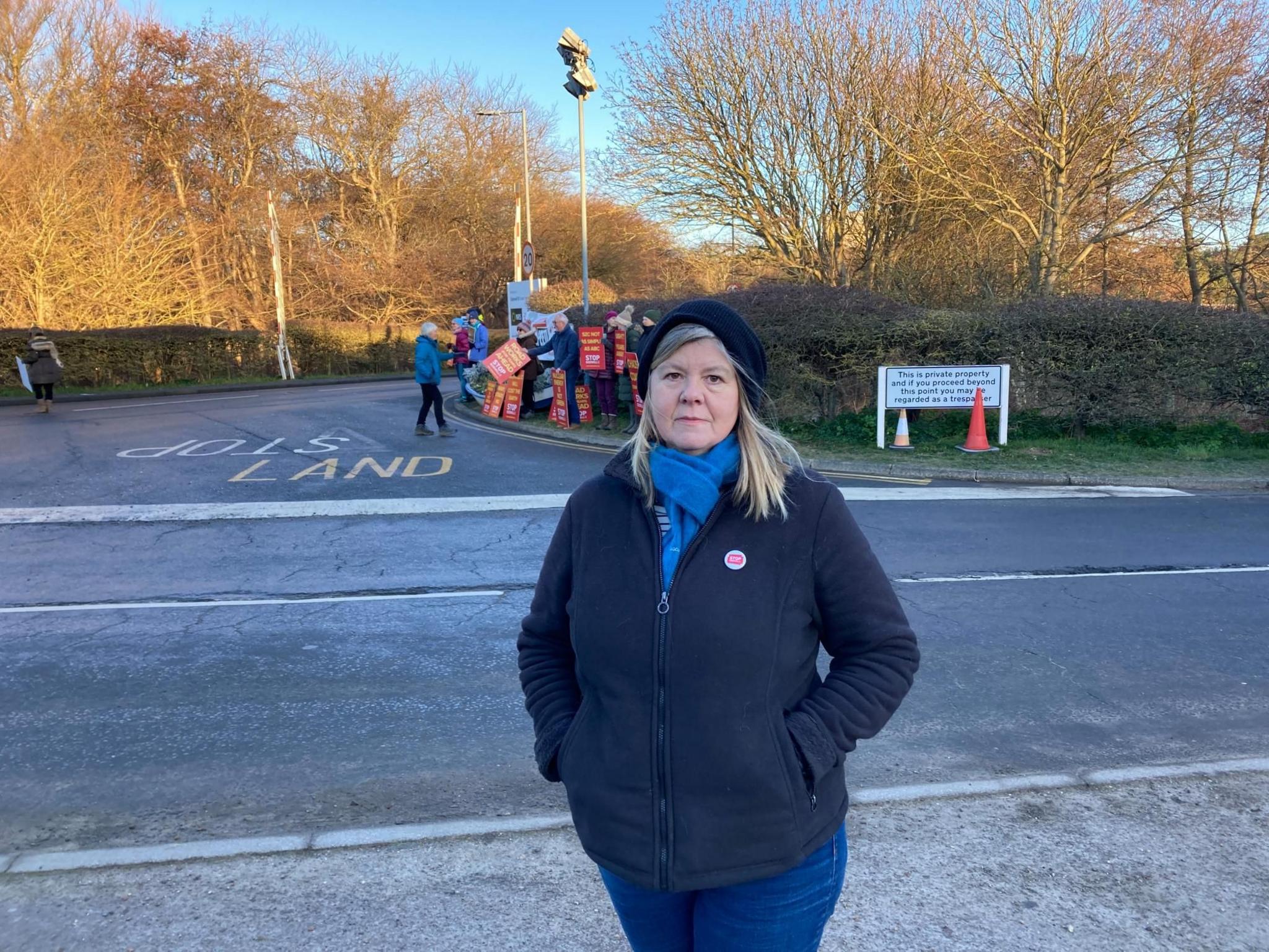 Alison Downes wearing a hat stood in front of campaigners near the Sizewell nuclear site