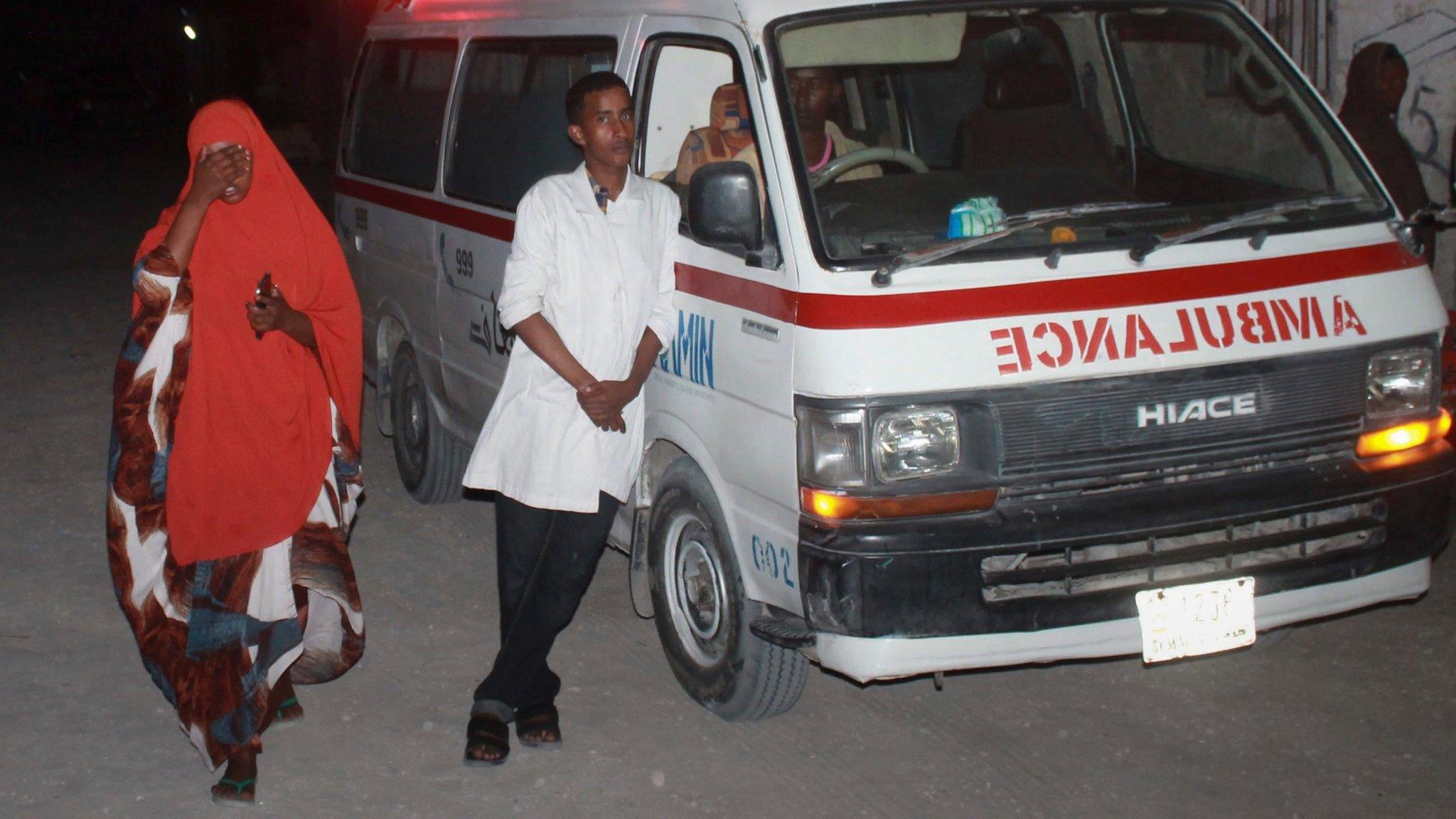 Ambulance workers stand by near the Lido beach where gunmen exploded a car bomb and opened fire at a restaurant in Mogadishu, Somalia, 21 January 2016.