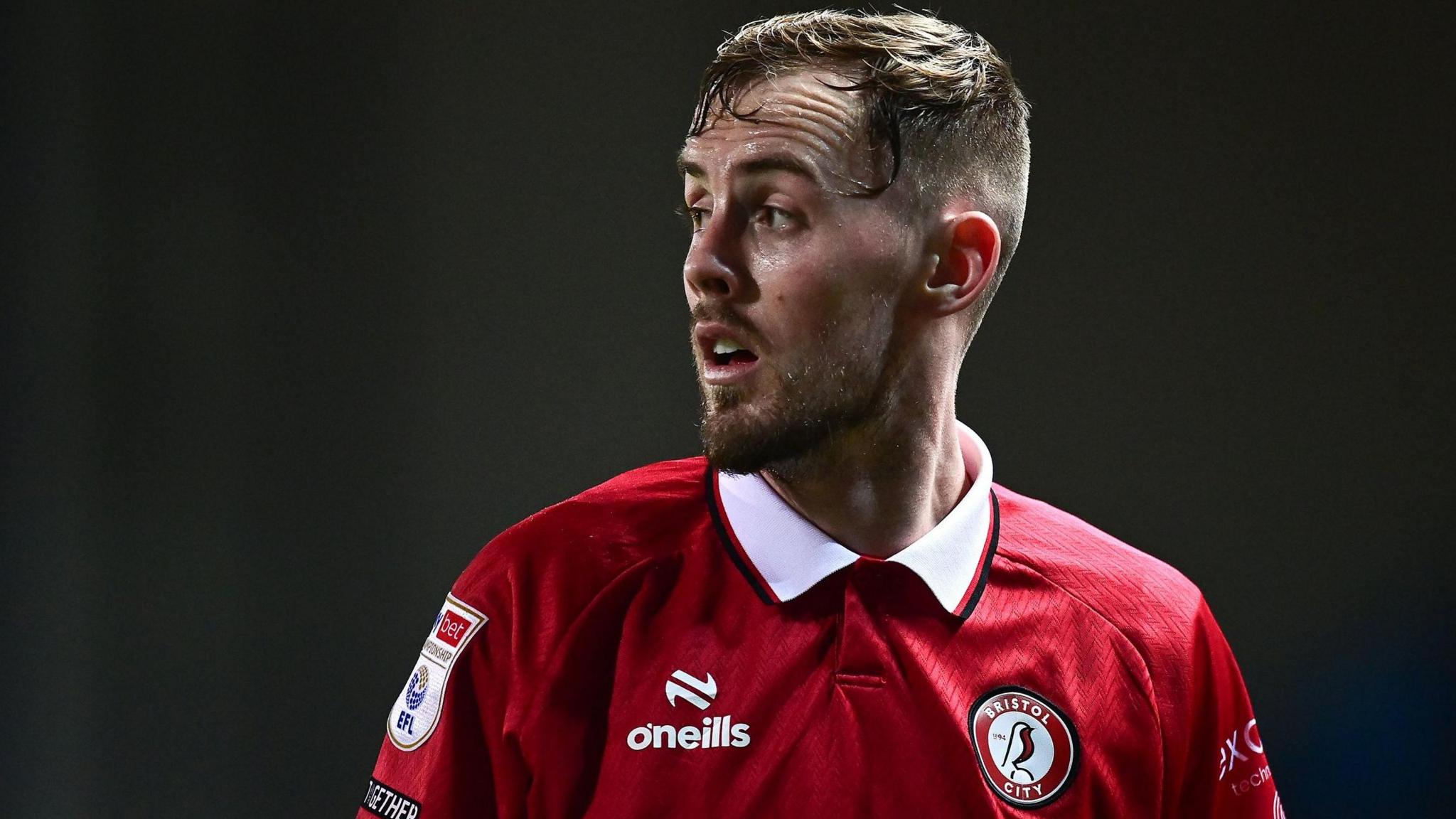 Mark Sykes wearing a red Bristol City shirt, is in action for the club.