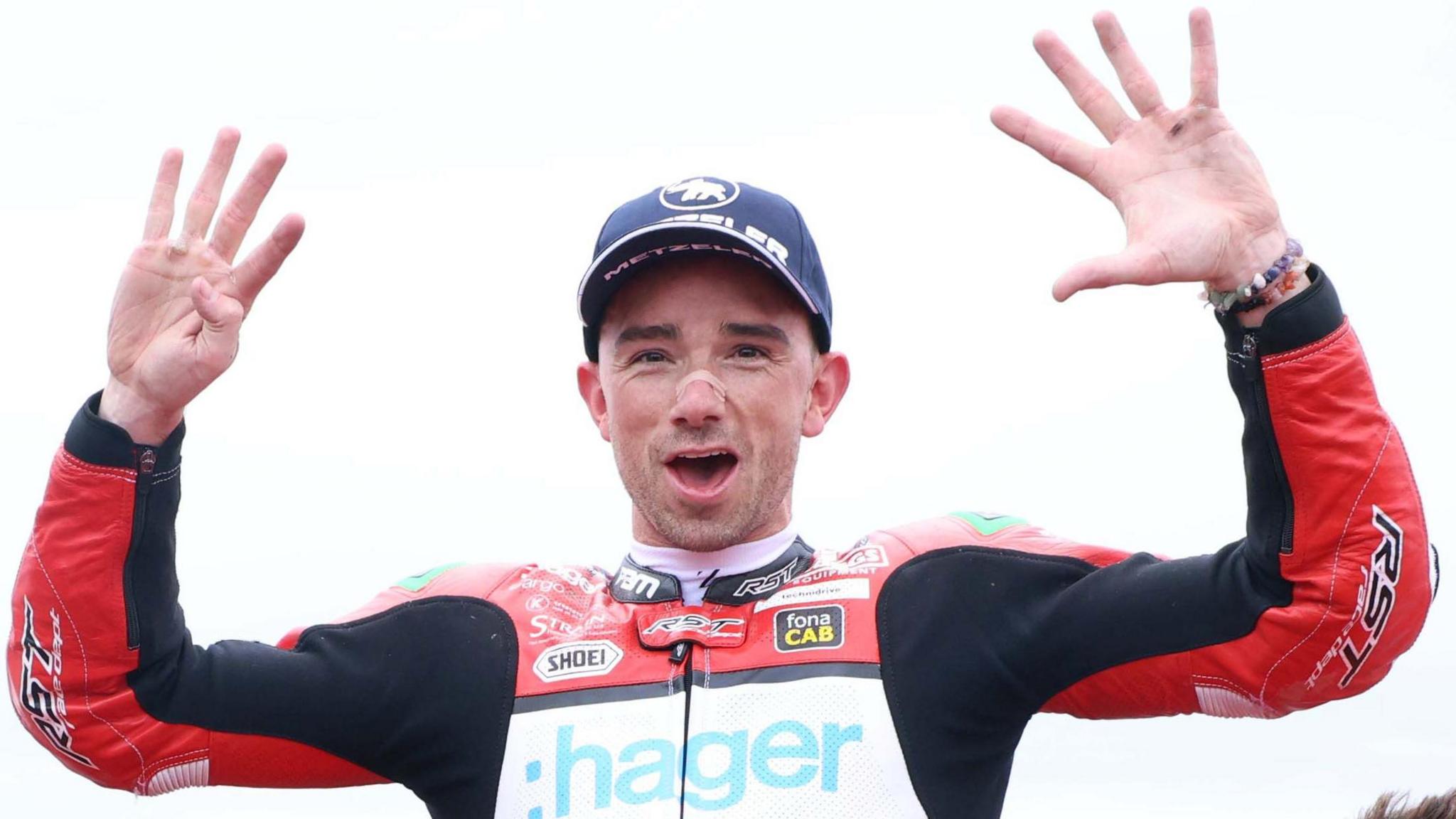 Glenn Irwin in a celebratory pose with his hands raised and a smile on his face