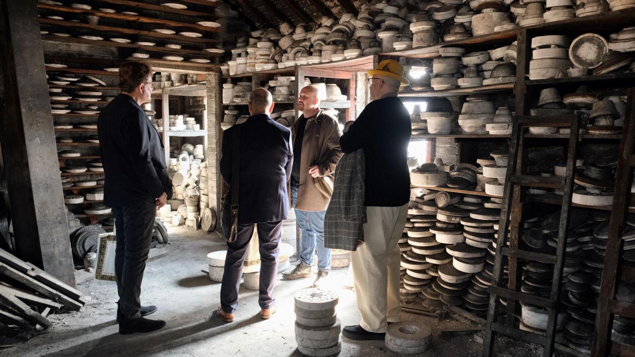 Jurors from World Craft Cities are inside a Stoke pottery store looking at a range of crockery that packs shelves around them