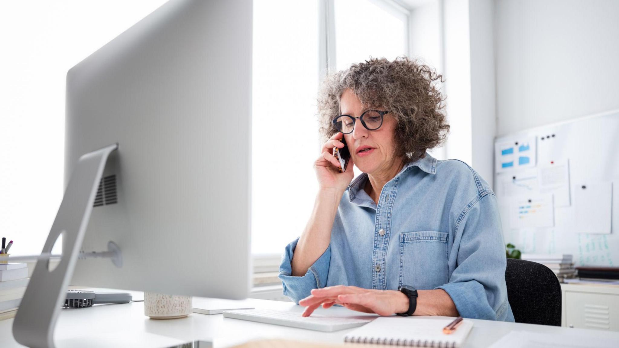 A woman sitting at a desk on the phone