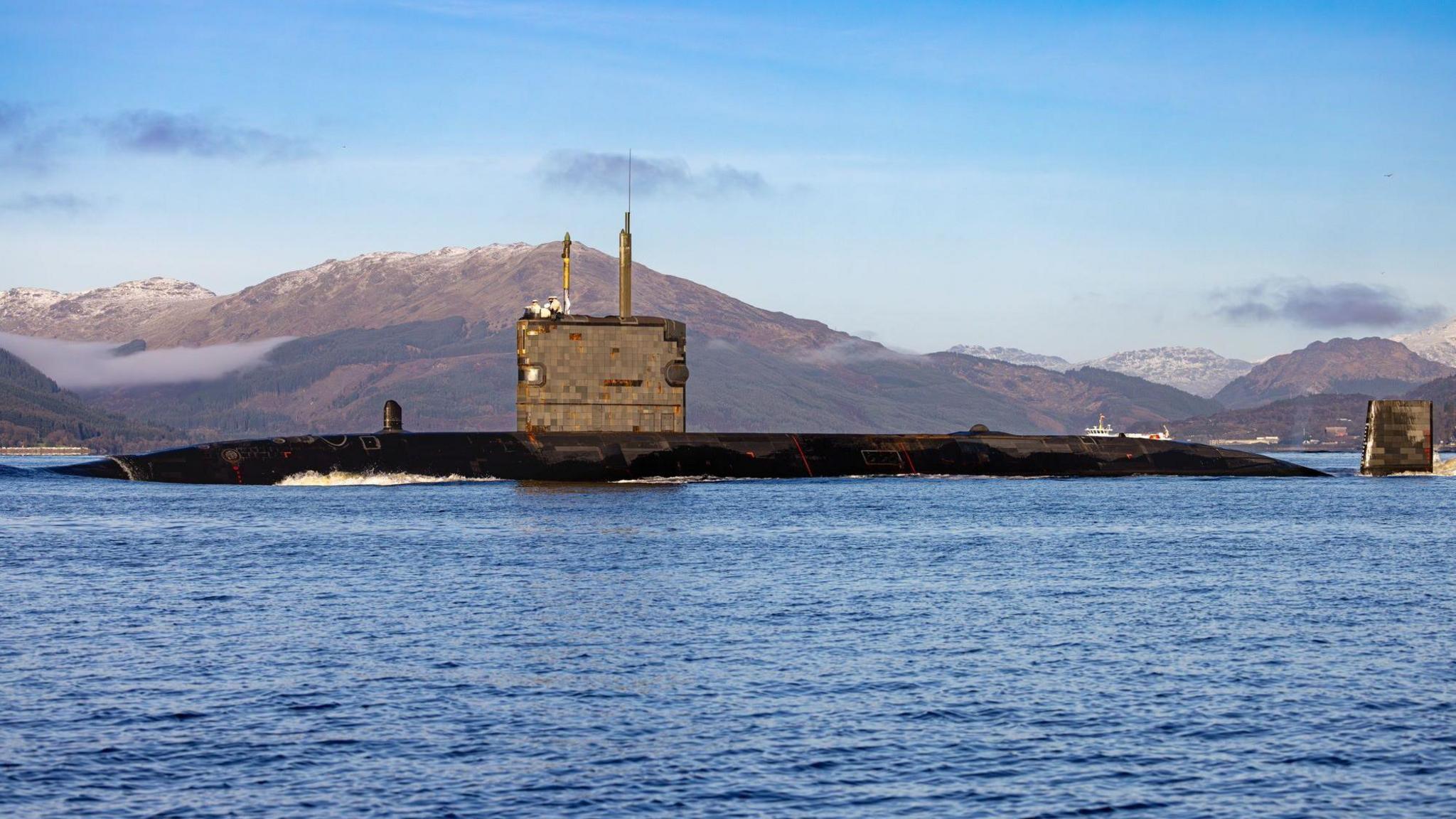 HMS Triumph at sea on a bright sunny day with blue skies and clear blue water