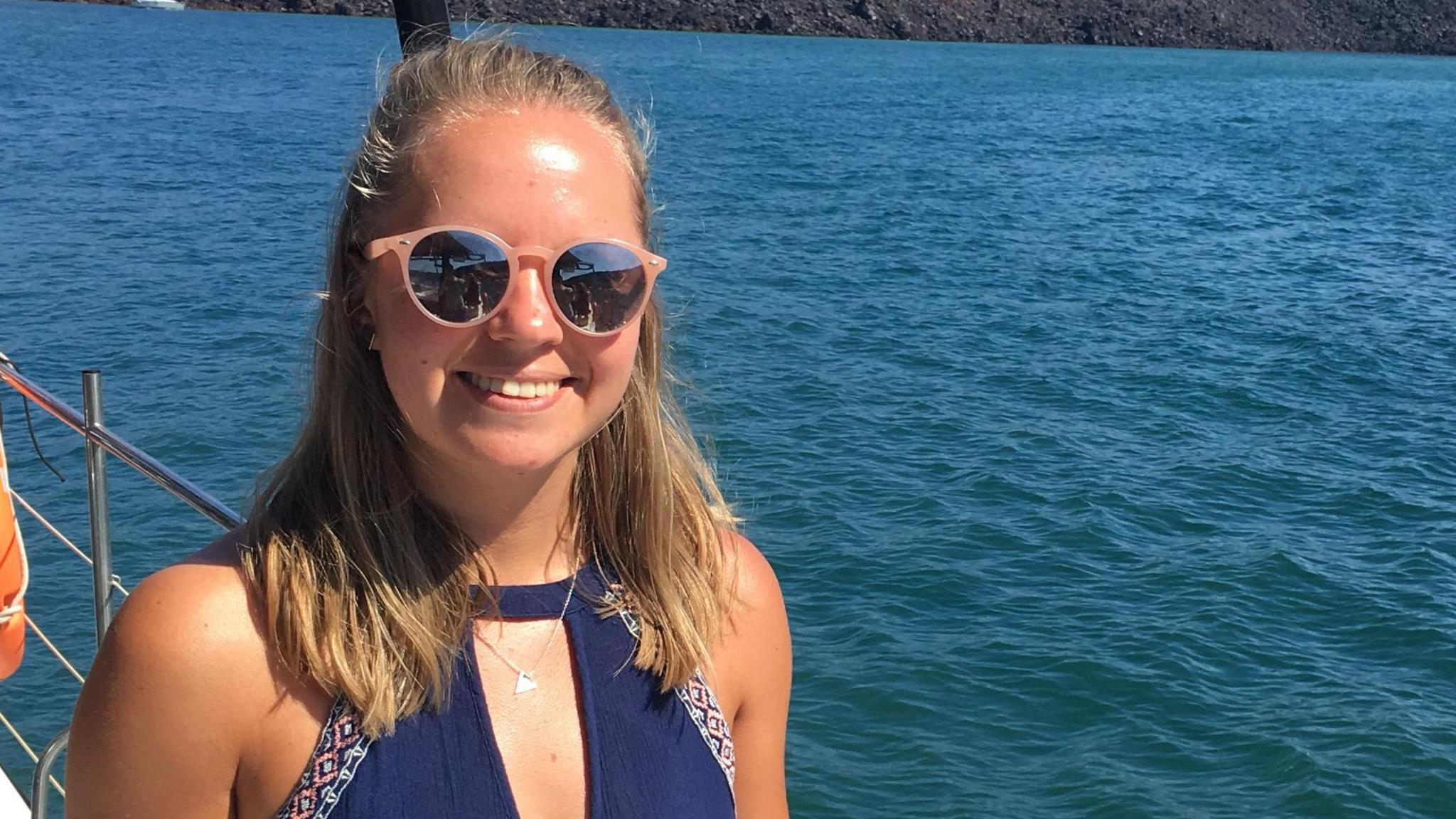 Poppy Devey Waterhouse smiling into the camera. She is on a boat with the sea in the background.
