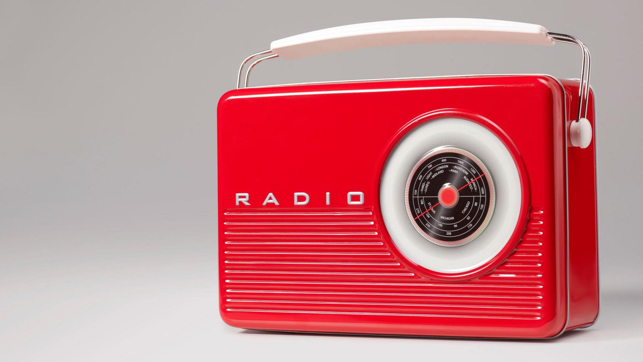 The radio is bright red with the word "radio" along the front. There is a large dial with radio frequencies.