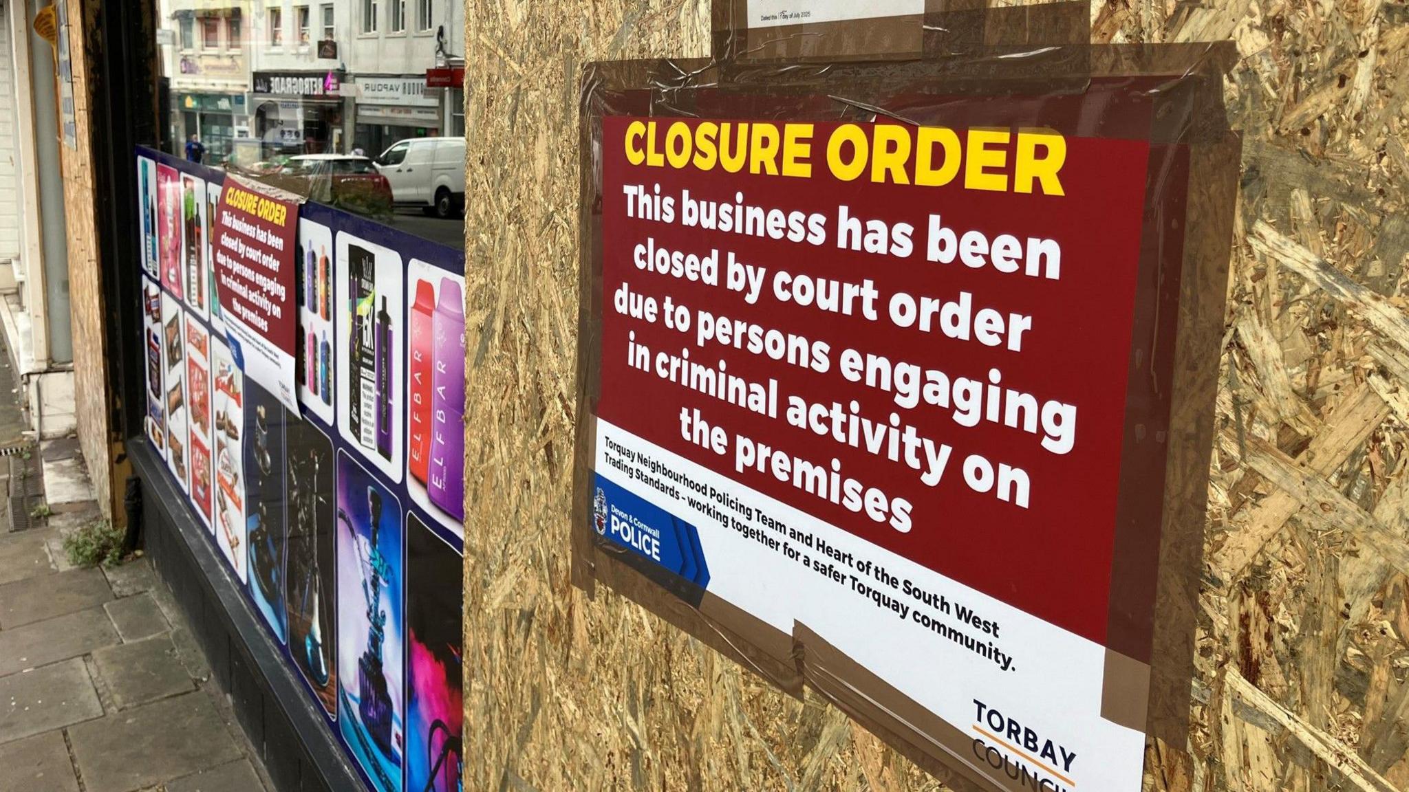The outside of a boarded up shop in Torbay with a big closure order poster displayed.