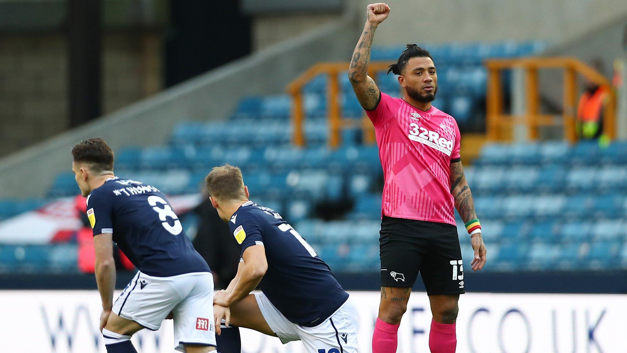 Derby County's Colin Kazim-Richards raises his fist as Millwall players take a knee