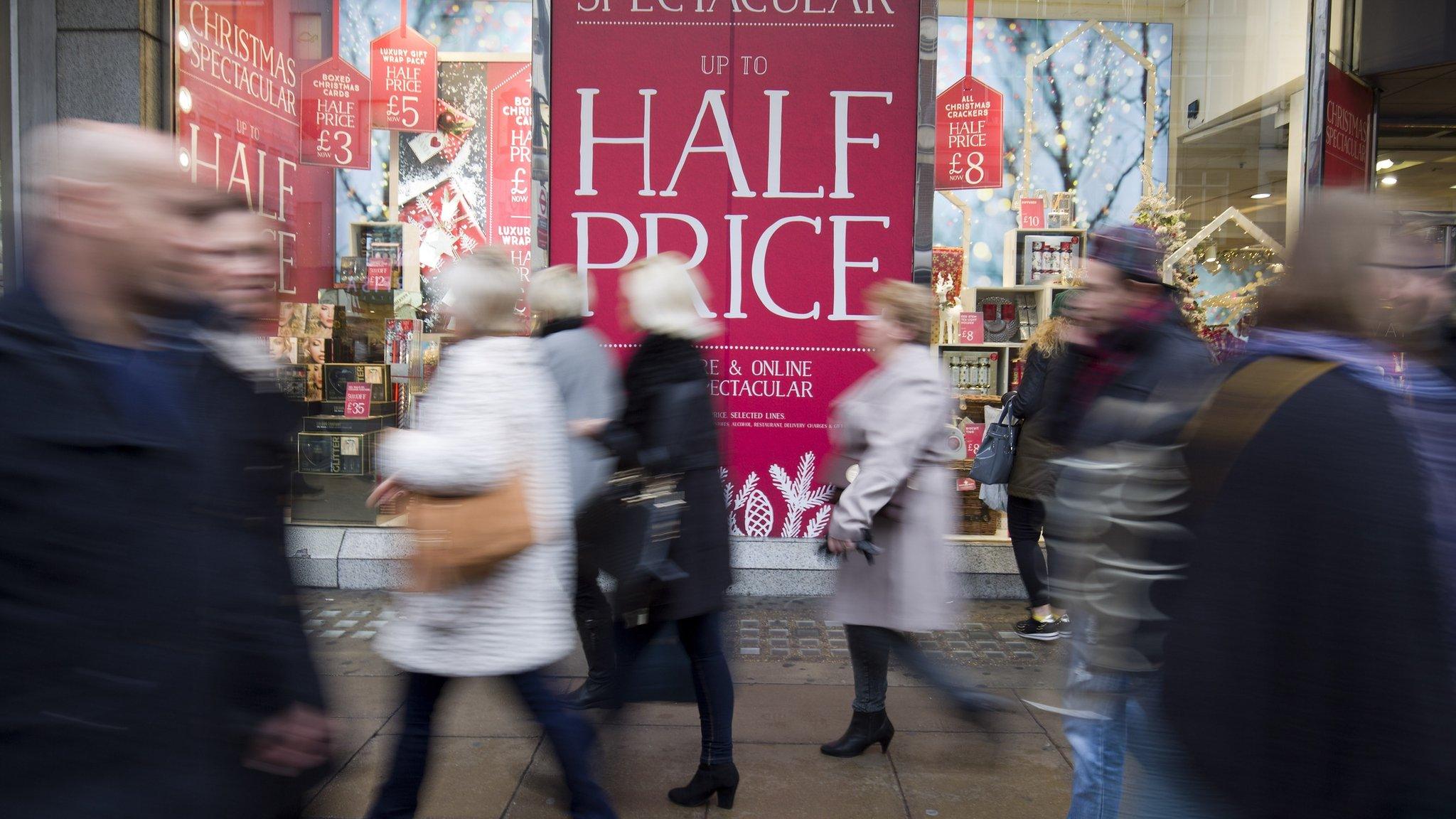 Pedestrians pass a sale sign on Oxford Street in central London