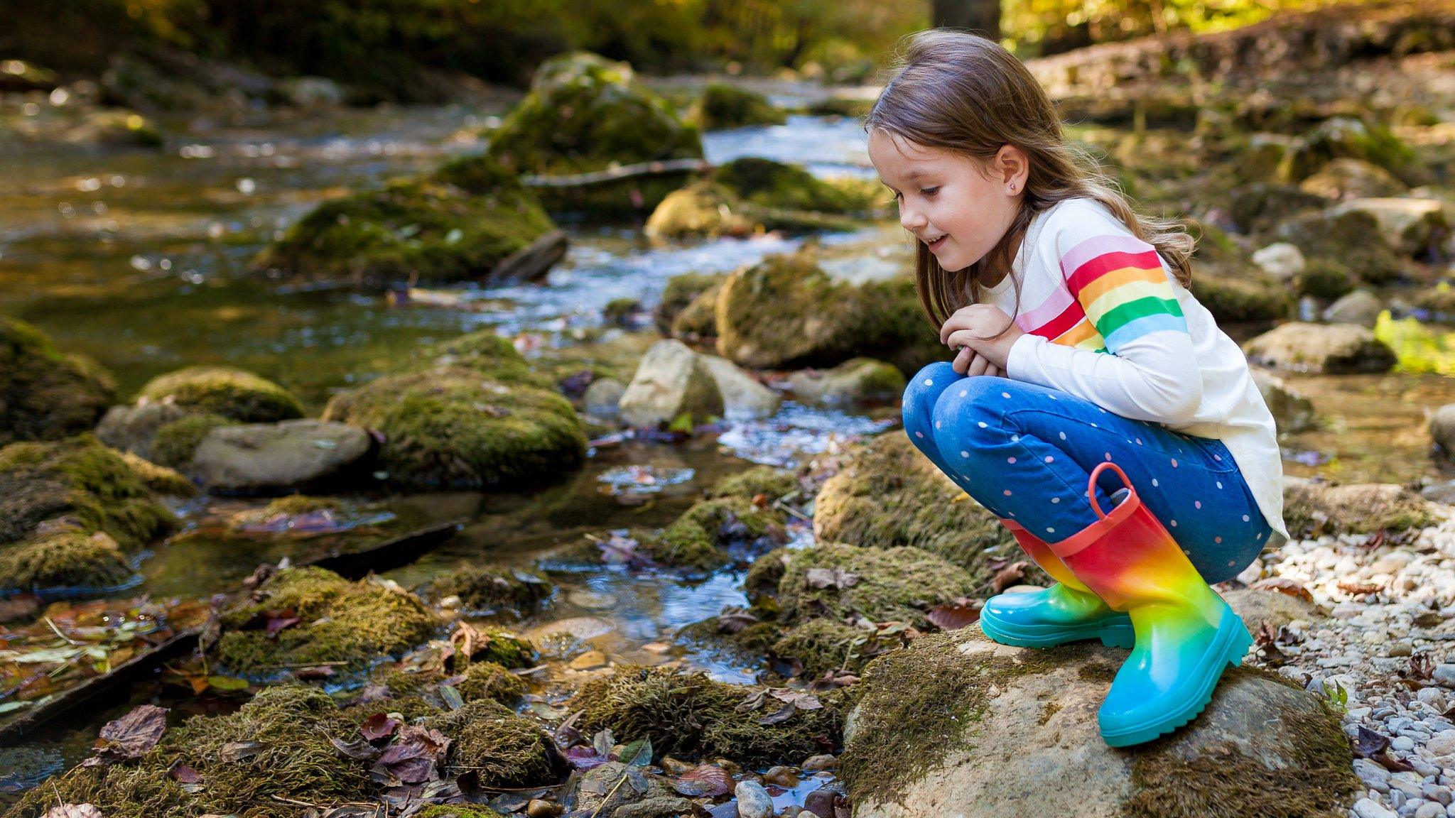 Girl sitting near shallow river