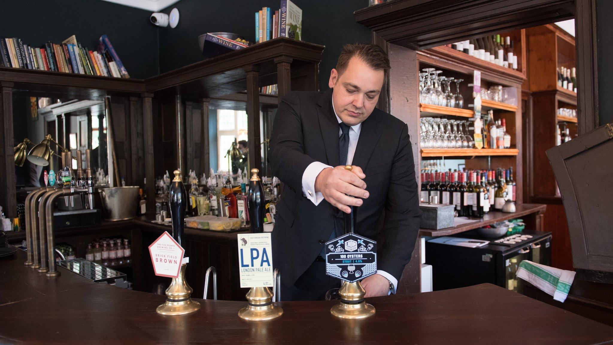 Man pulls a pint of beer behind the bar