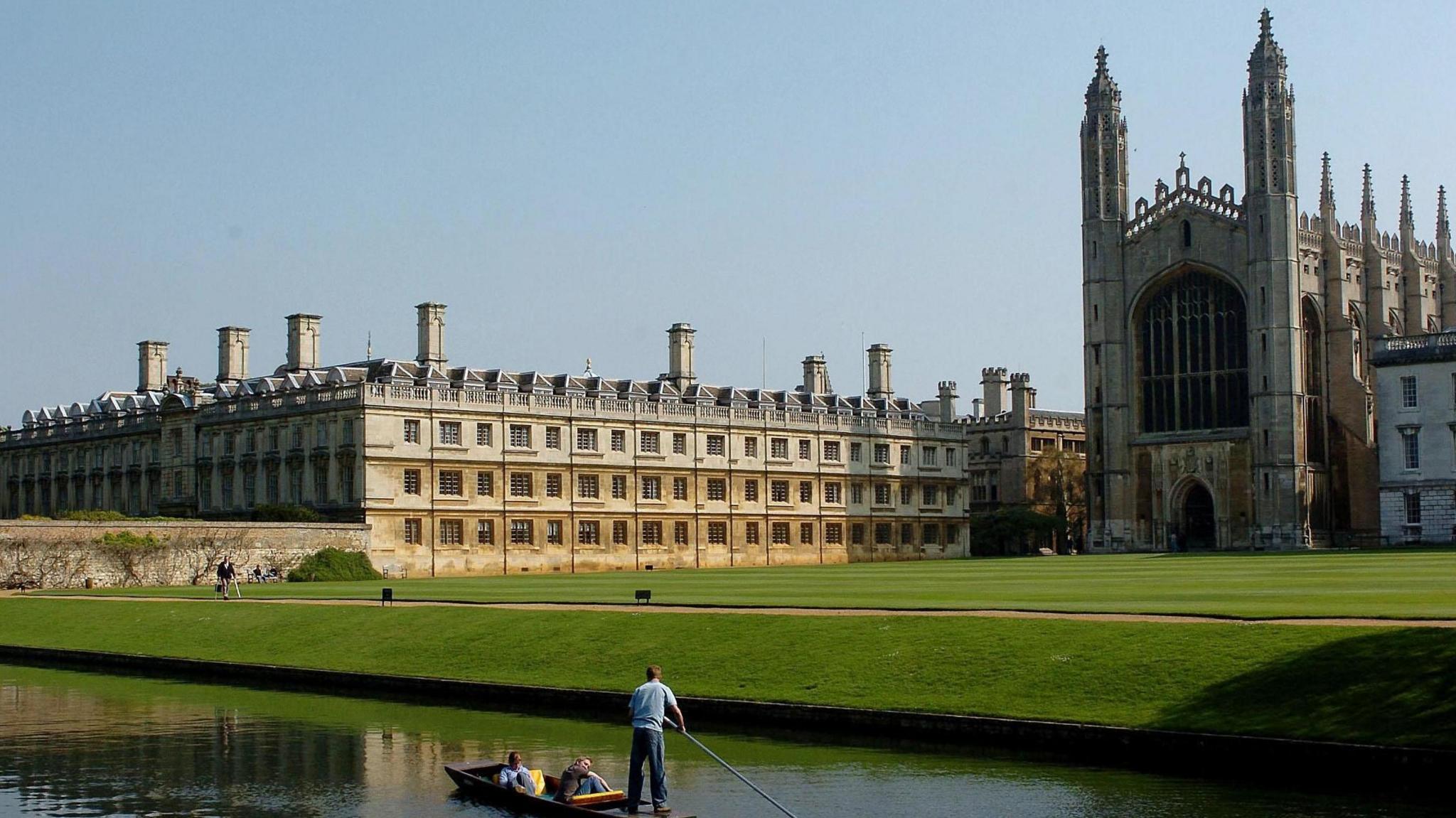 Three people on a punt on the Backs in Cambridge as it passes King's College.