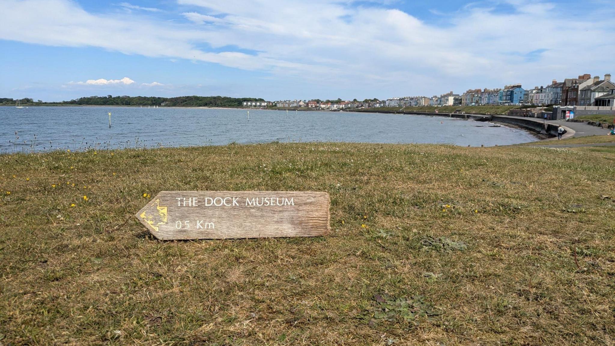 The sign, this time resting on the grass pointing towards the sea.