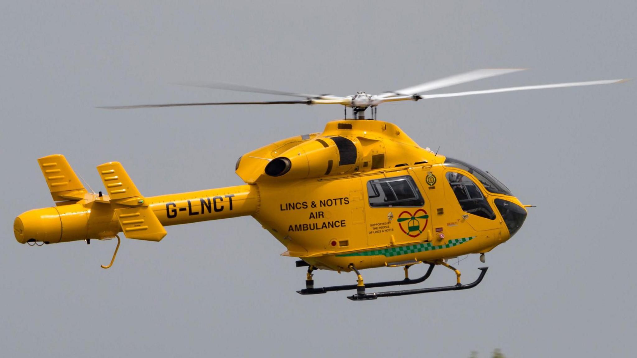 A yellow helicopter in the air.