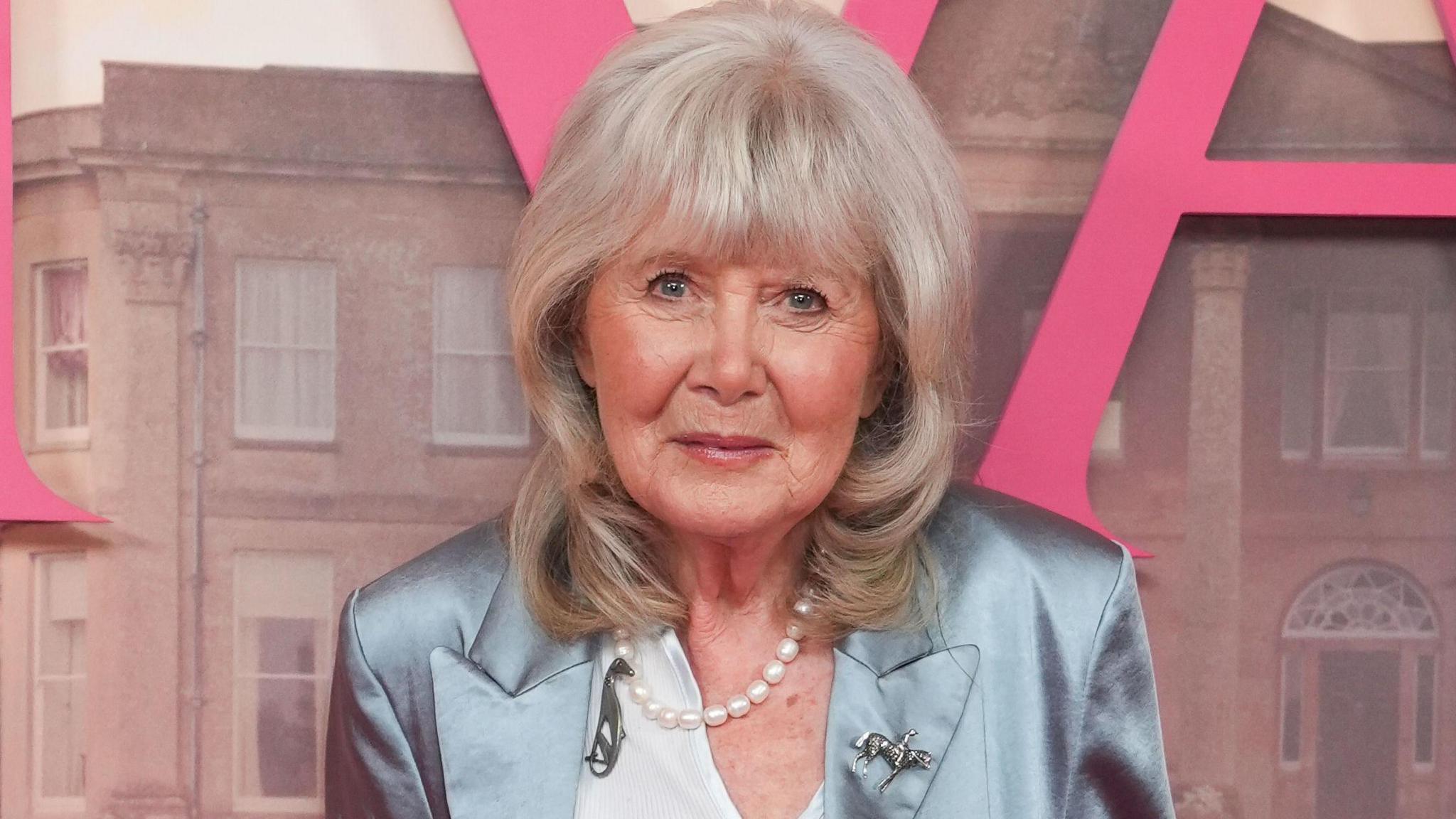 Dame Jilly Cooper at the premiere of Rivals standing against a poster for the Disney+ series.