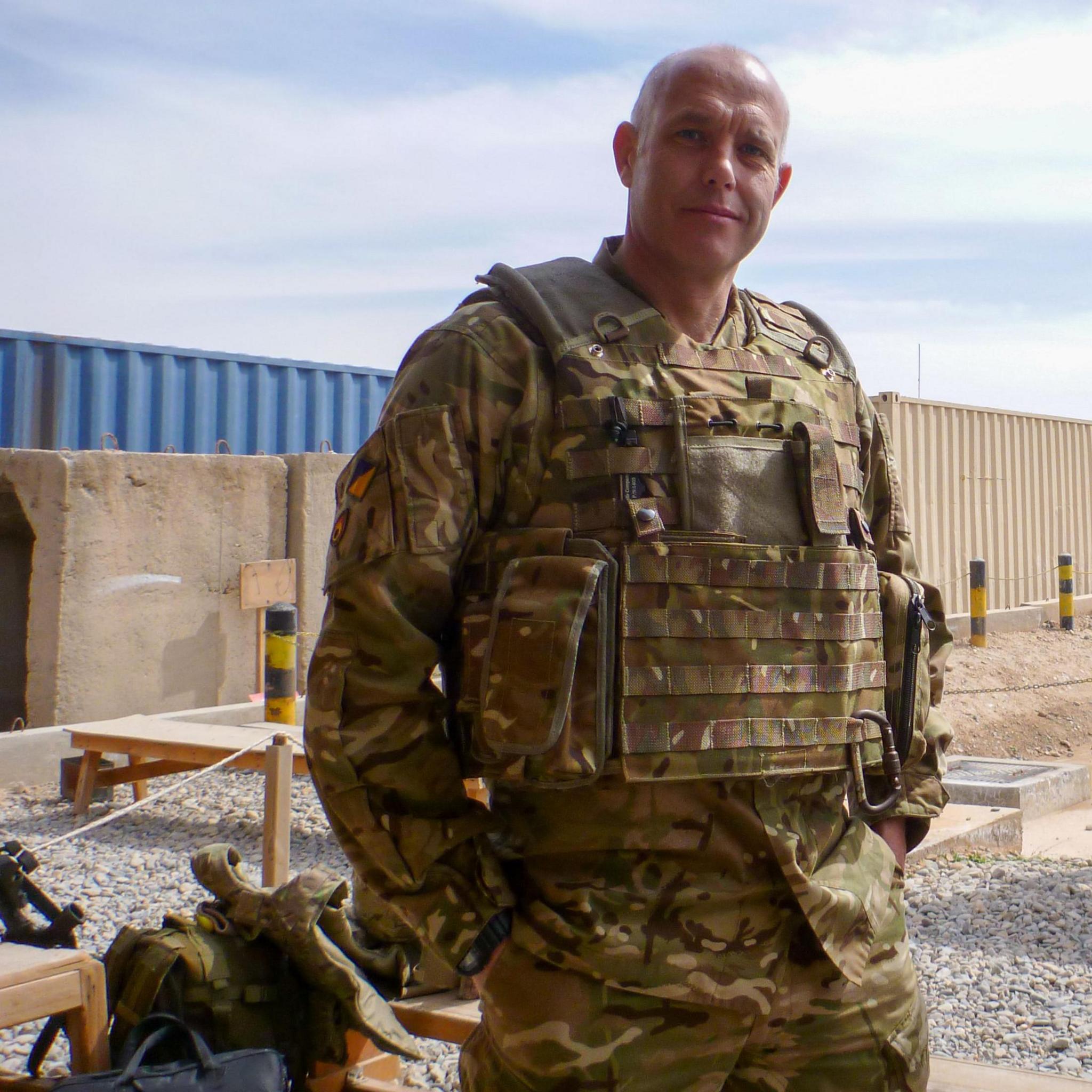 In combat fatigues, a balding Gareth is looking directly into the camera, whilst posing for a photo in Afghanistan.