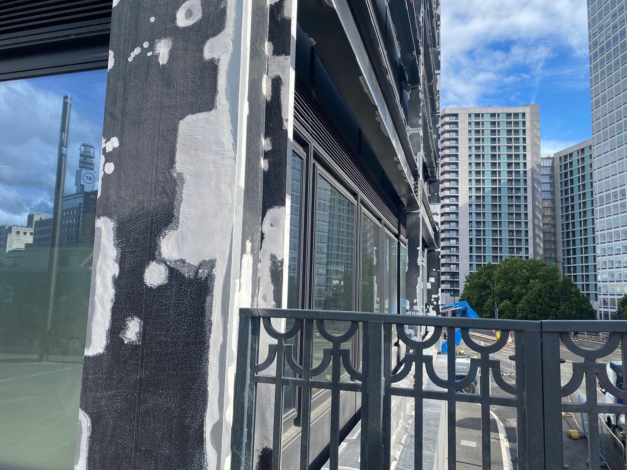 A picture showing the corner of a steel and glass building, showing many white splotches on a grey steel pillar.