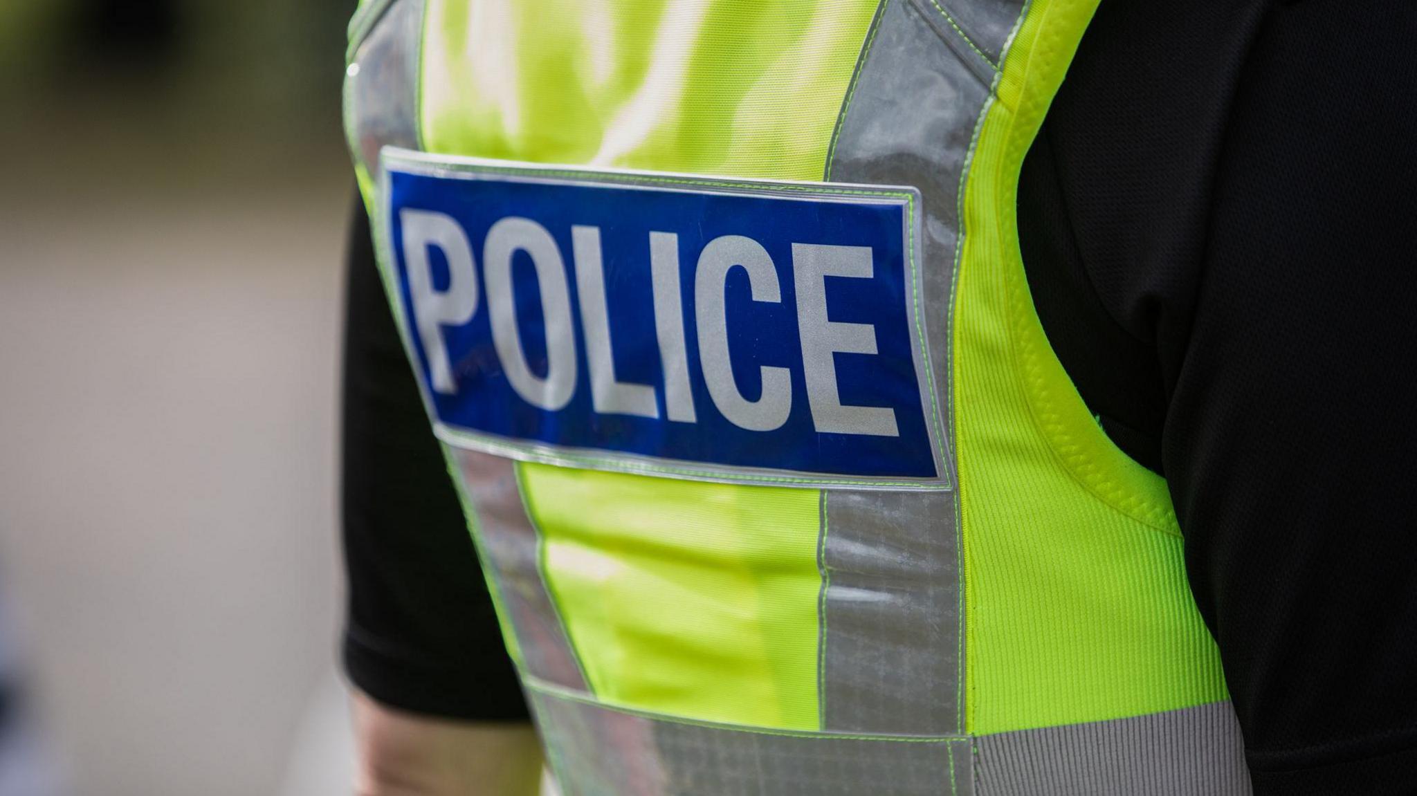 A close up stock image of the back of a police officers high vis vest